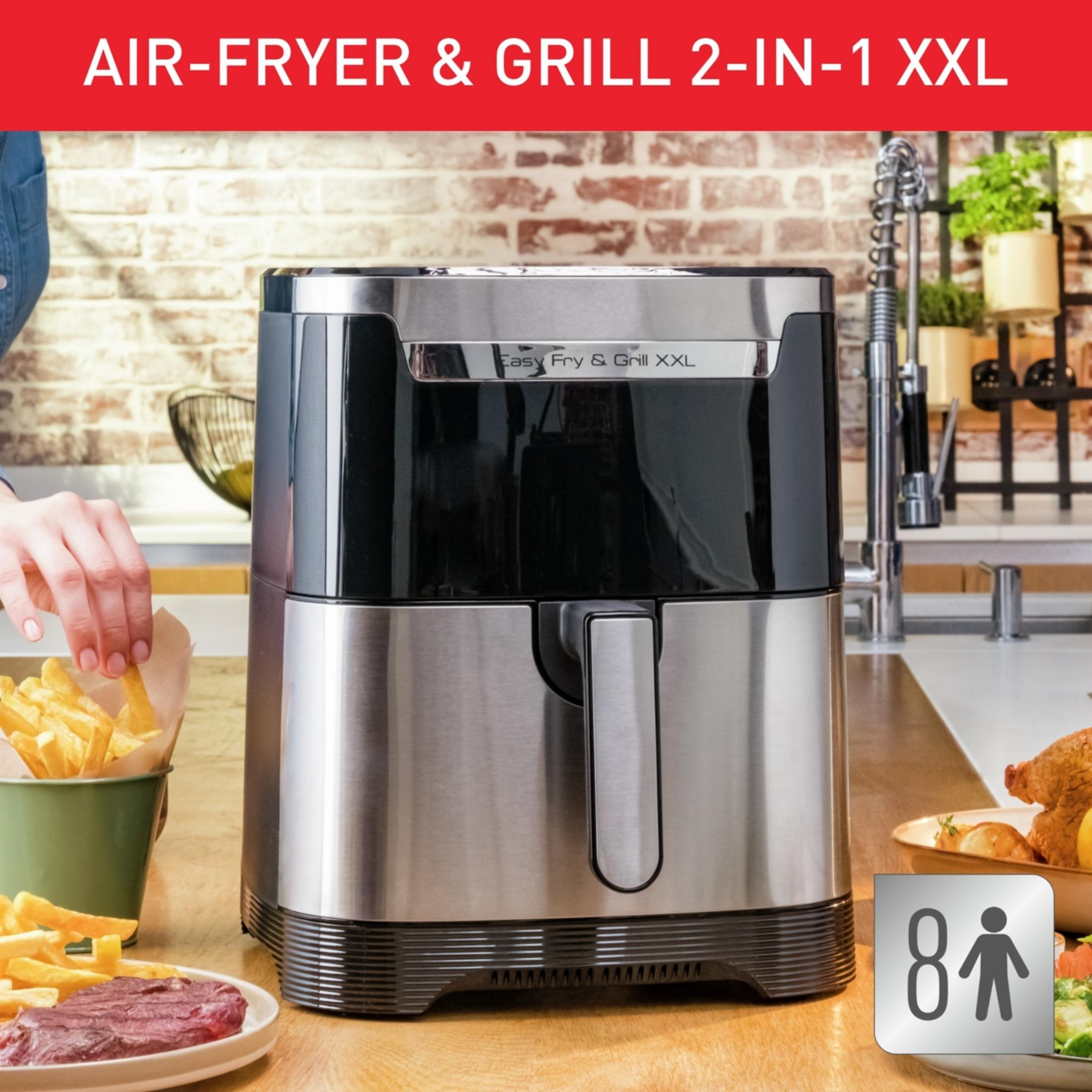 A silver air fryer grill sits on a wooden table with fries and steak.