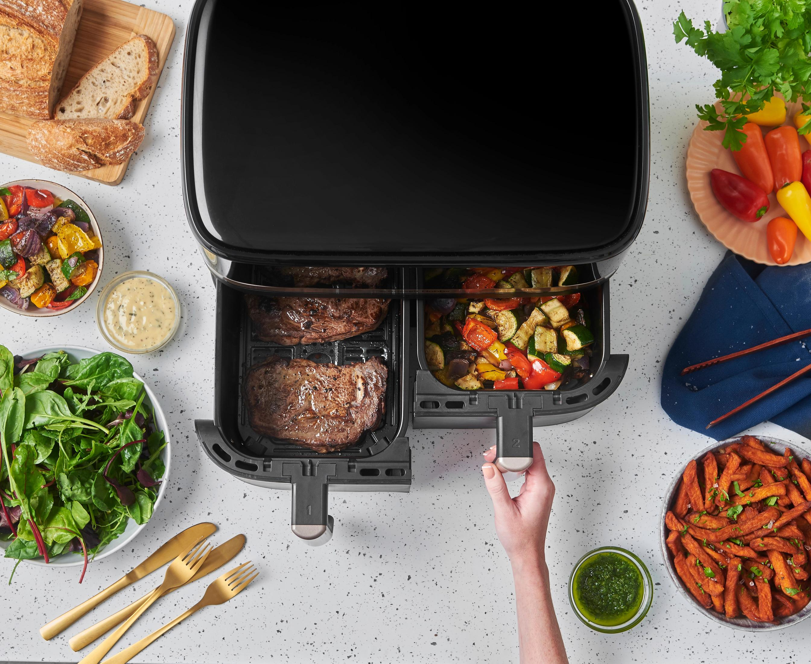 Podwójna frytownica beztłuszczowa ze stekami i warzywami, chlebem, sałatką i frytkami.