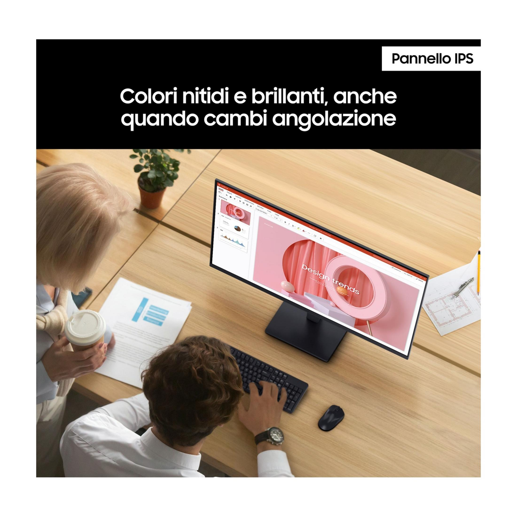 Twee mensen werken aan een bureau met een monitor. Eén typt, de ander houdt koffie vast.