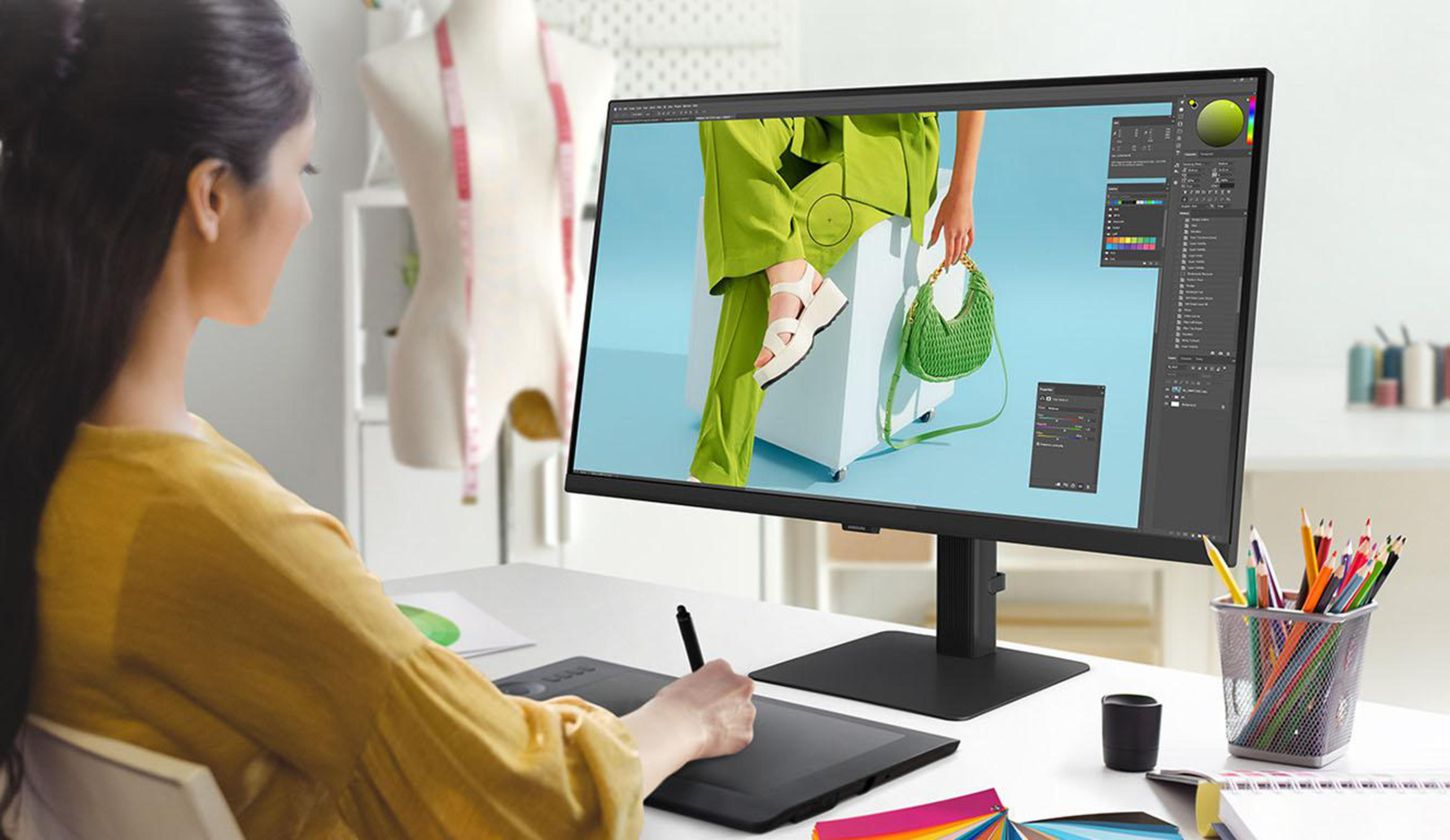 Kobieta pracuje przy komputerze z oprogramowaniem do projektowania graficznego, narzędziami i materiałami.