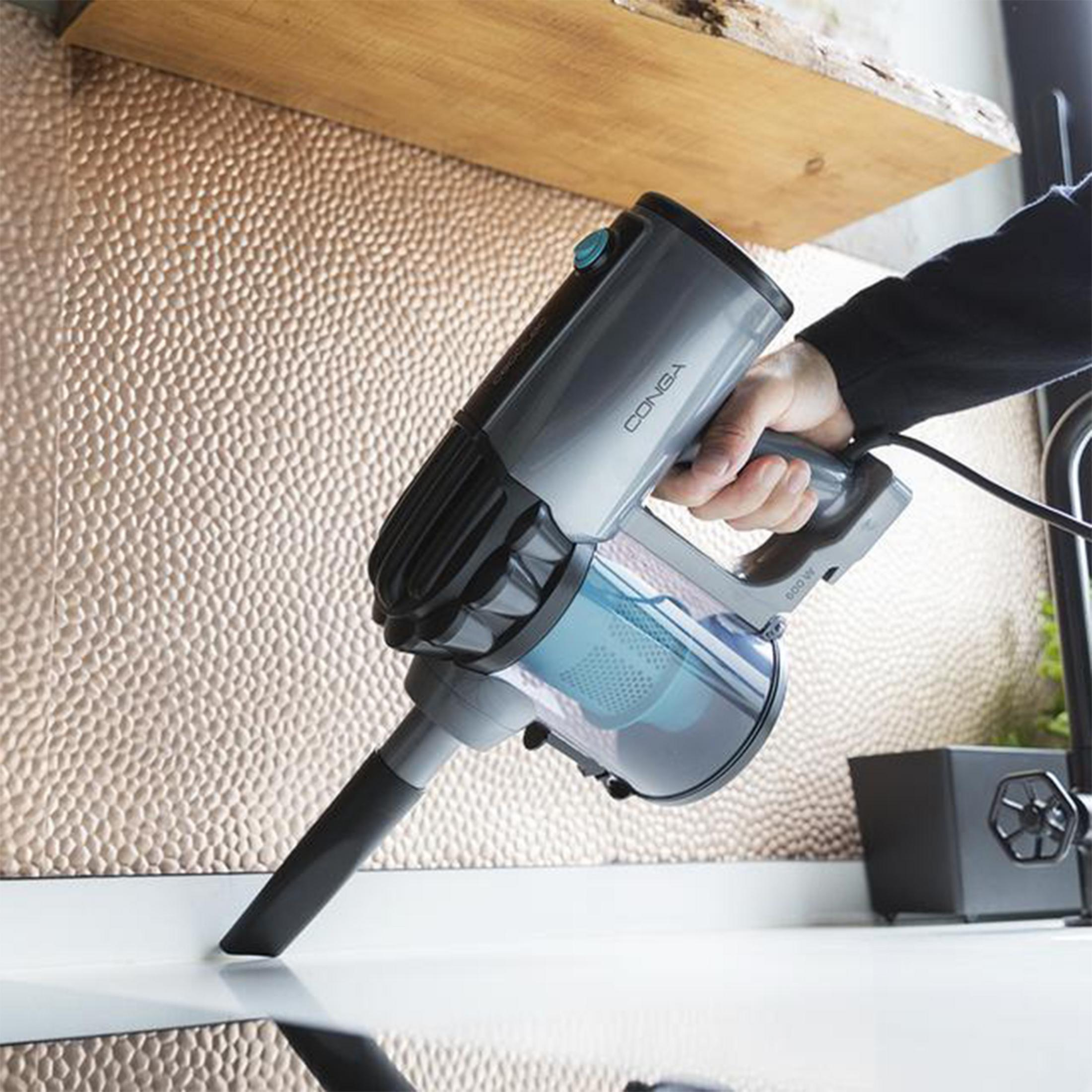 Gray handheld vacuum cleaner being used on a white surface, close-up.