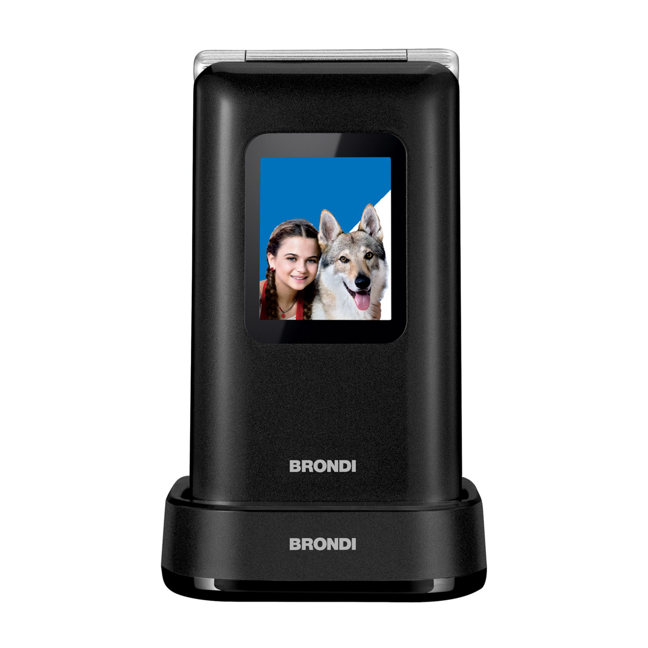 Un teléfono plegable negro muestra una niña y un perro en su pantalla, sobre una base de carga.