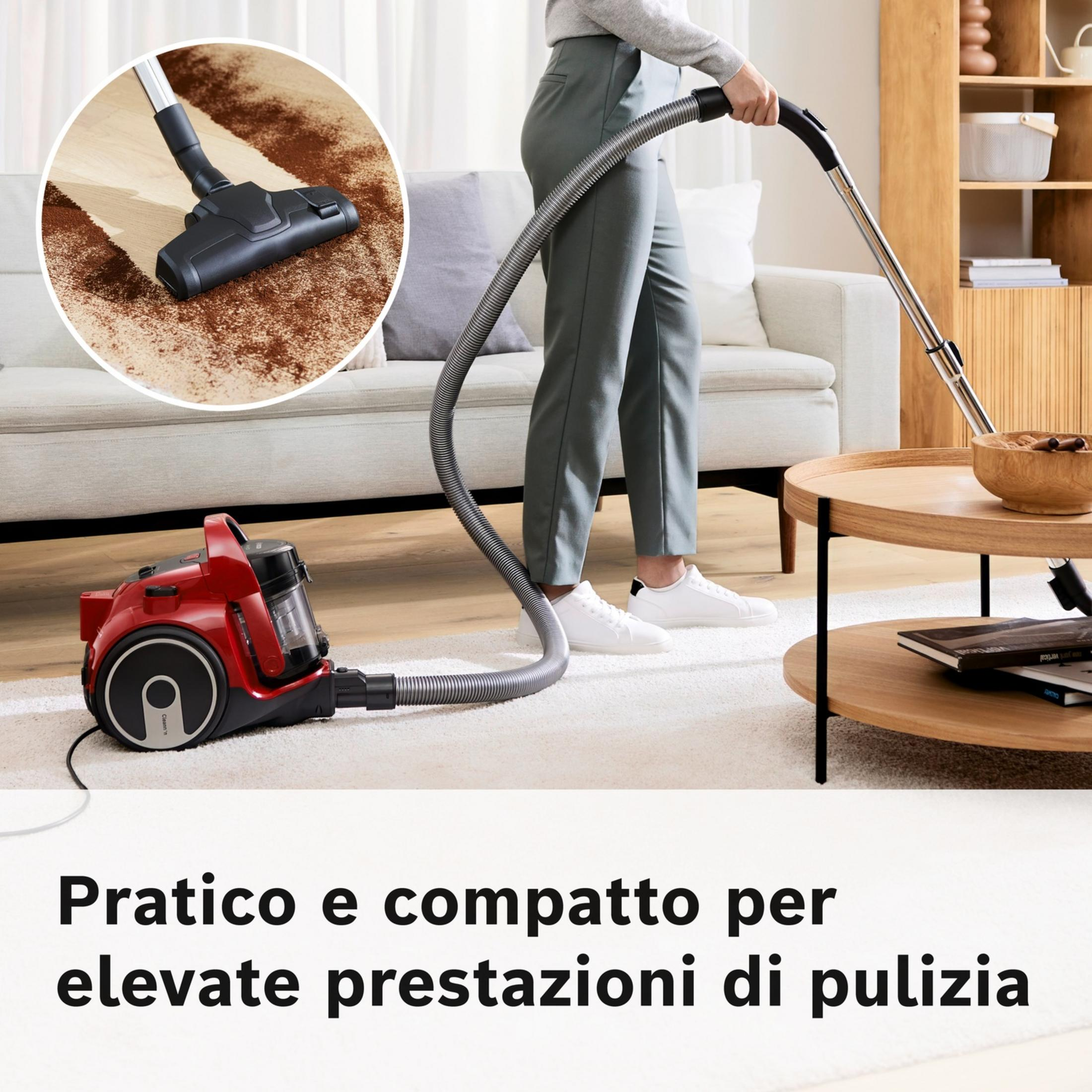 Czerwony odkurzacz odkurza dywan. Osoba odkurza dywan w pokoju.