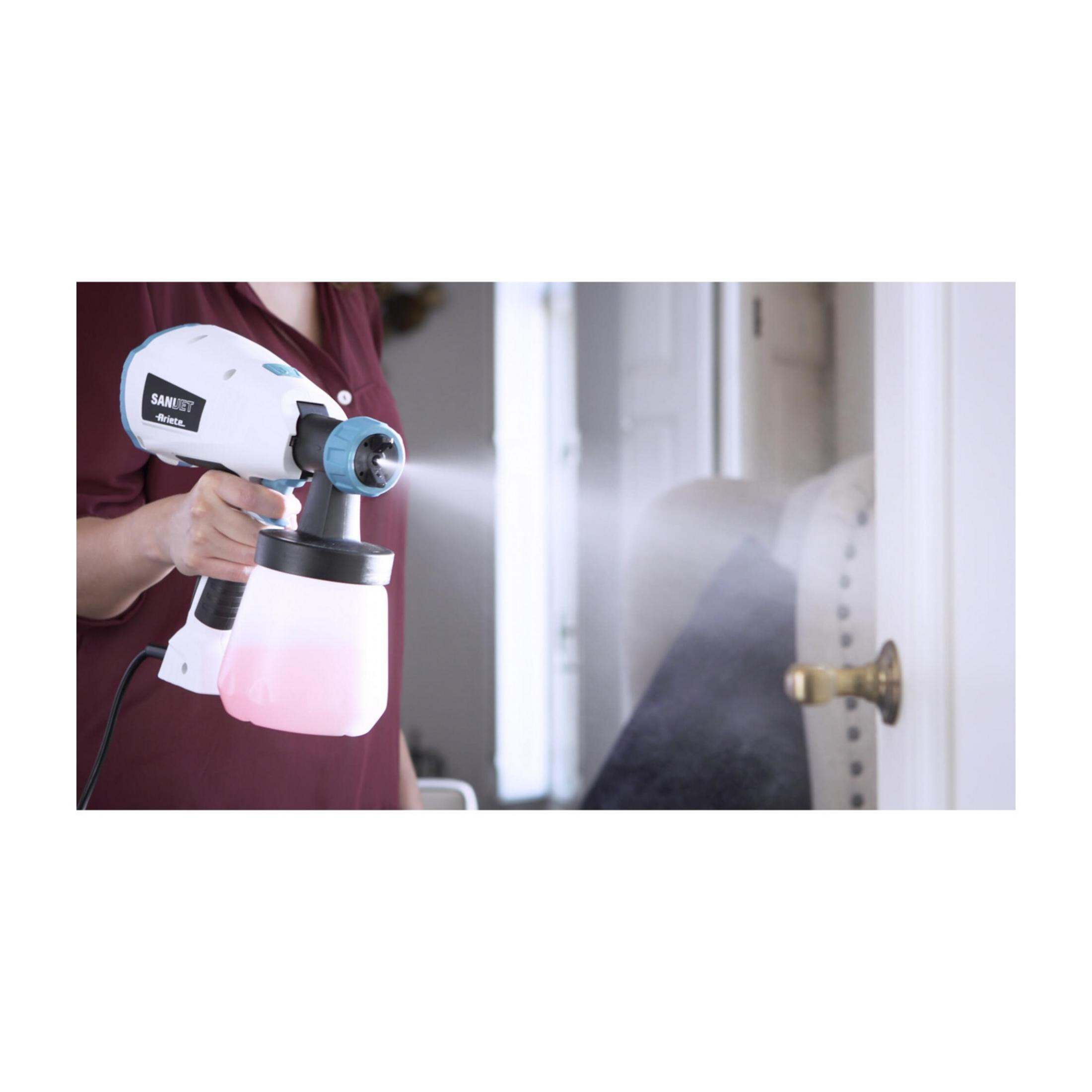 Persona spruzza una porta con un dispositivo bianco e blu contenente liquido rosa.