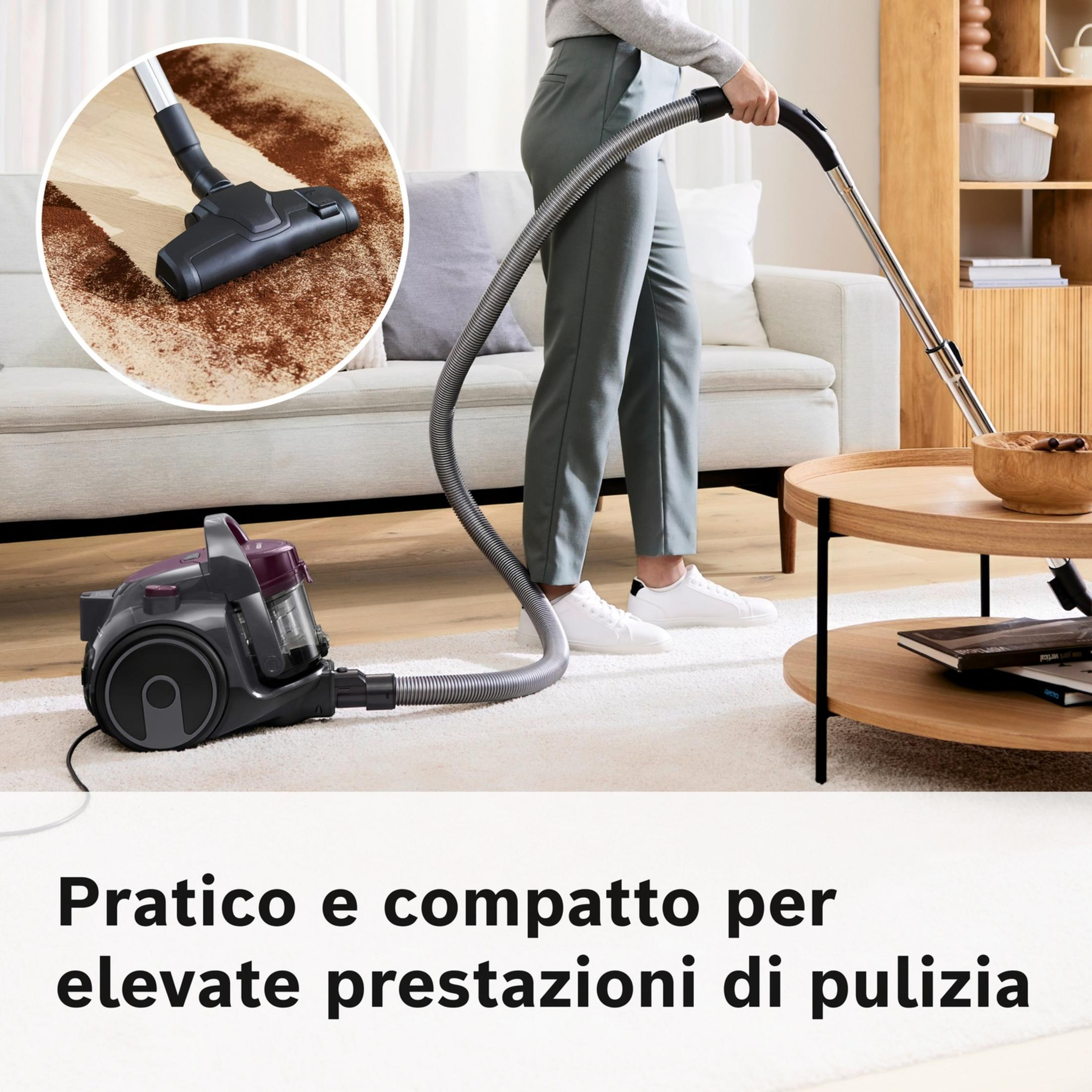 Osoba odkurza dywan szarym odkurzaczem w salonie.