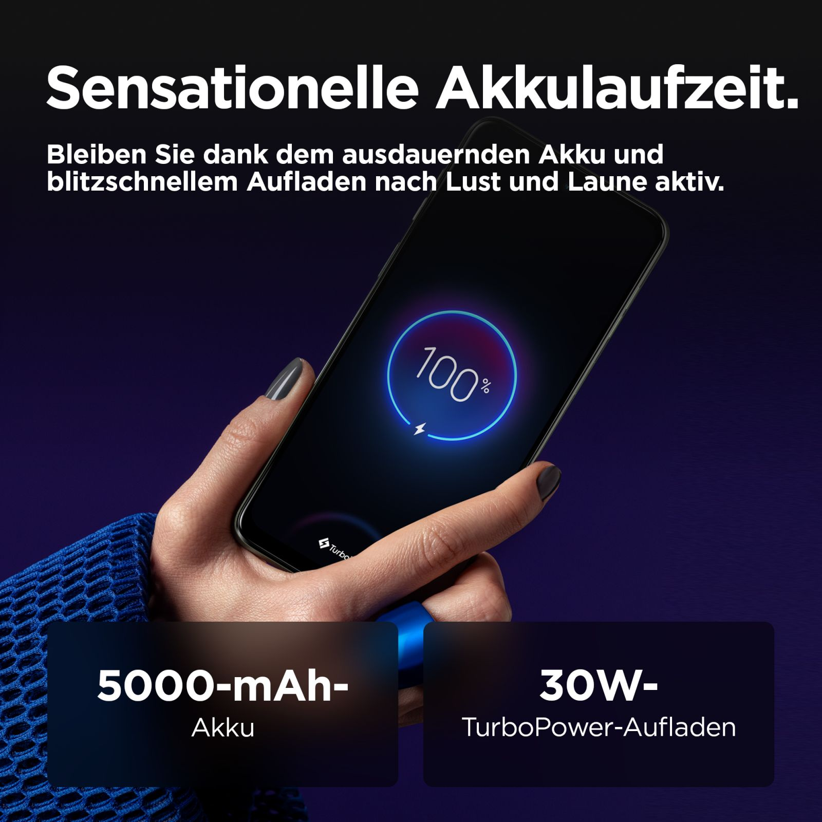 Dłoń trzyma smartfon naładowany w 100%. Bateria 5000 mAh i ładowanie TurboPower 30W.