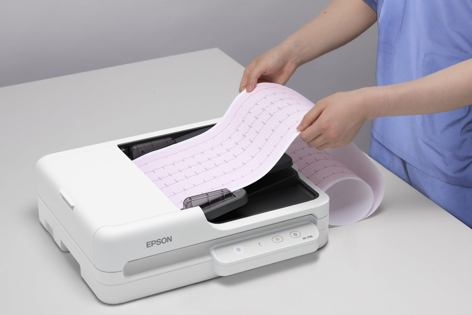 Handen houden ECG-papier vast boven een witte Epson printer.
