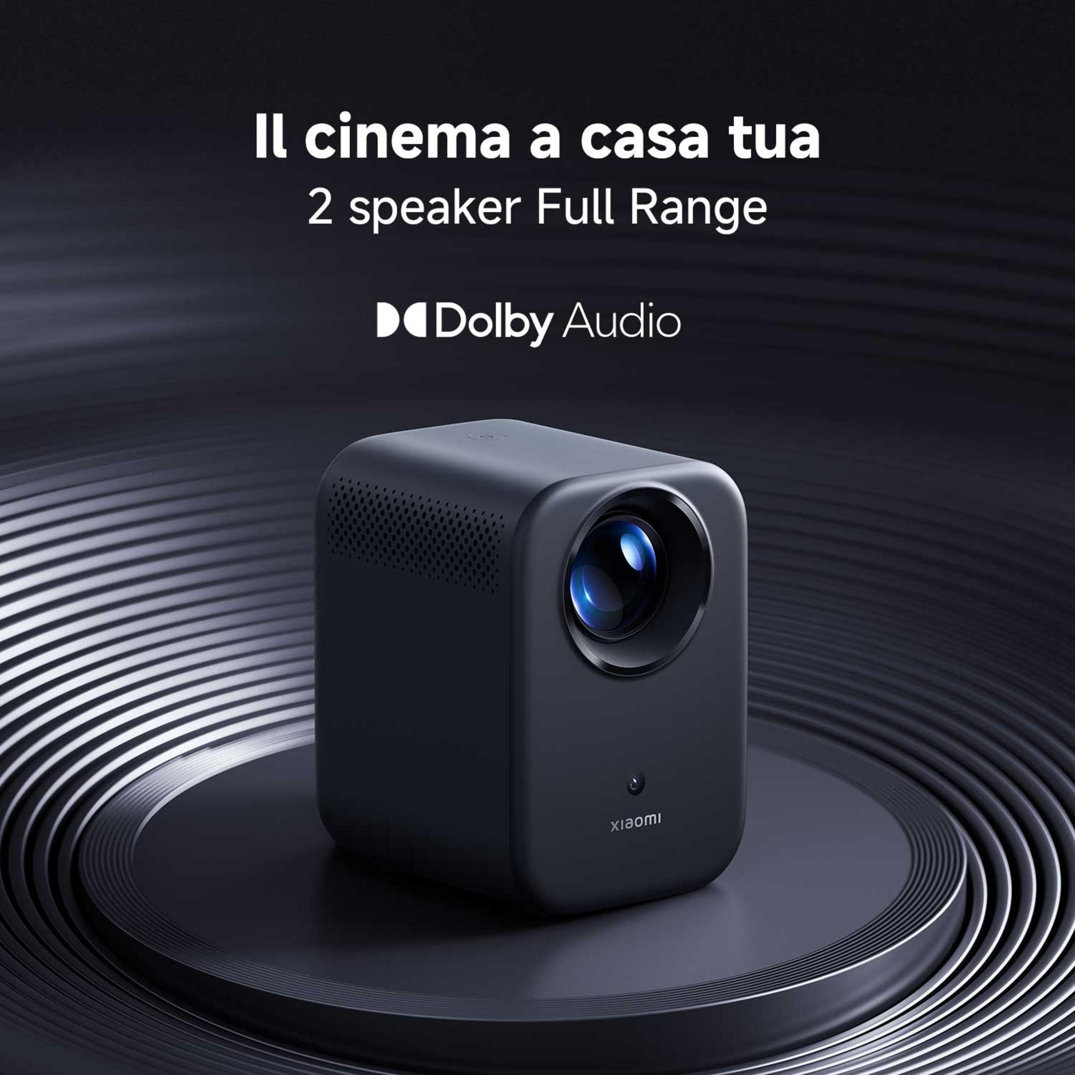 Czarny projektor z logo Dolby Audio stoi na ciemnej podstawie.