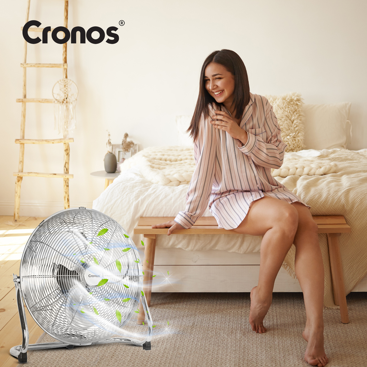 Wentylator Cronos dmucha powietrzem na uśmiechniętą kobietę w piżamie w sypialni.