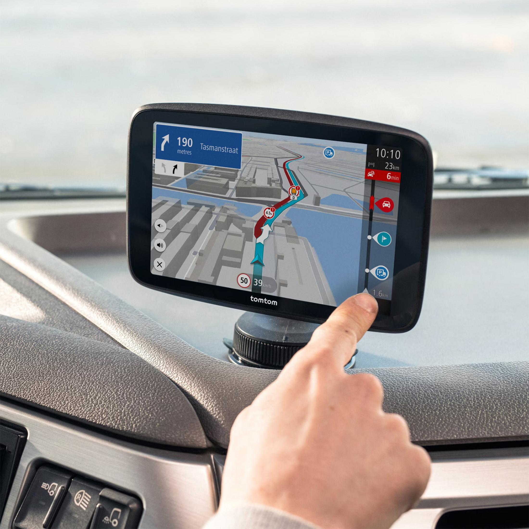 Un dedo toca una pantalla de navegación TomTom que muestra una ruta.