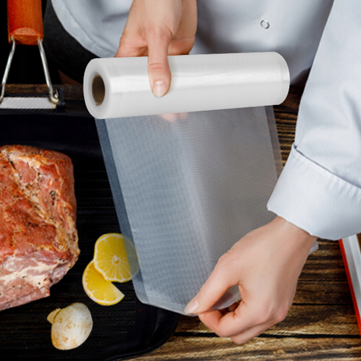 Kucharz trzyma rolkę próżniową nad mięsem, cytryną i grzybem na grillu.