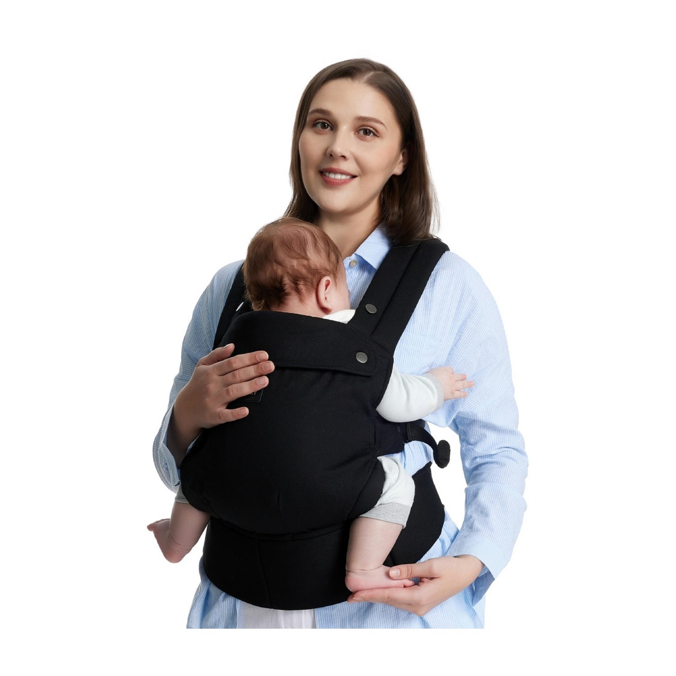 Woman holding a baby in a black carrier, wearing a blue striped shirt.
