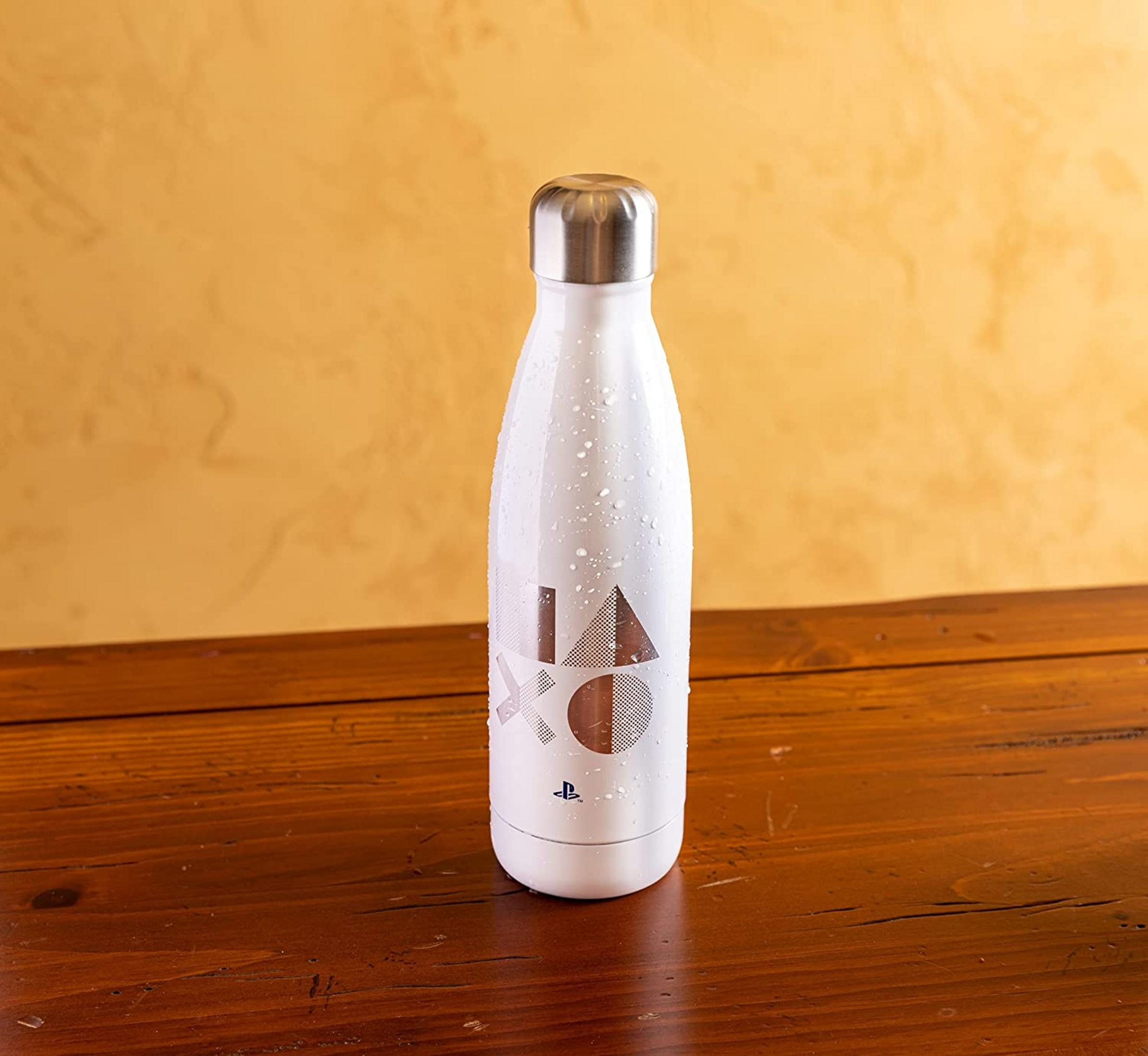 Eine weiße Flasche mit PlayStation-Symbolen steht auf einem Holztisch.