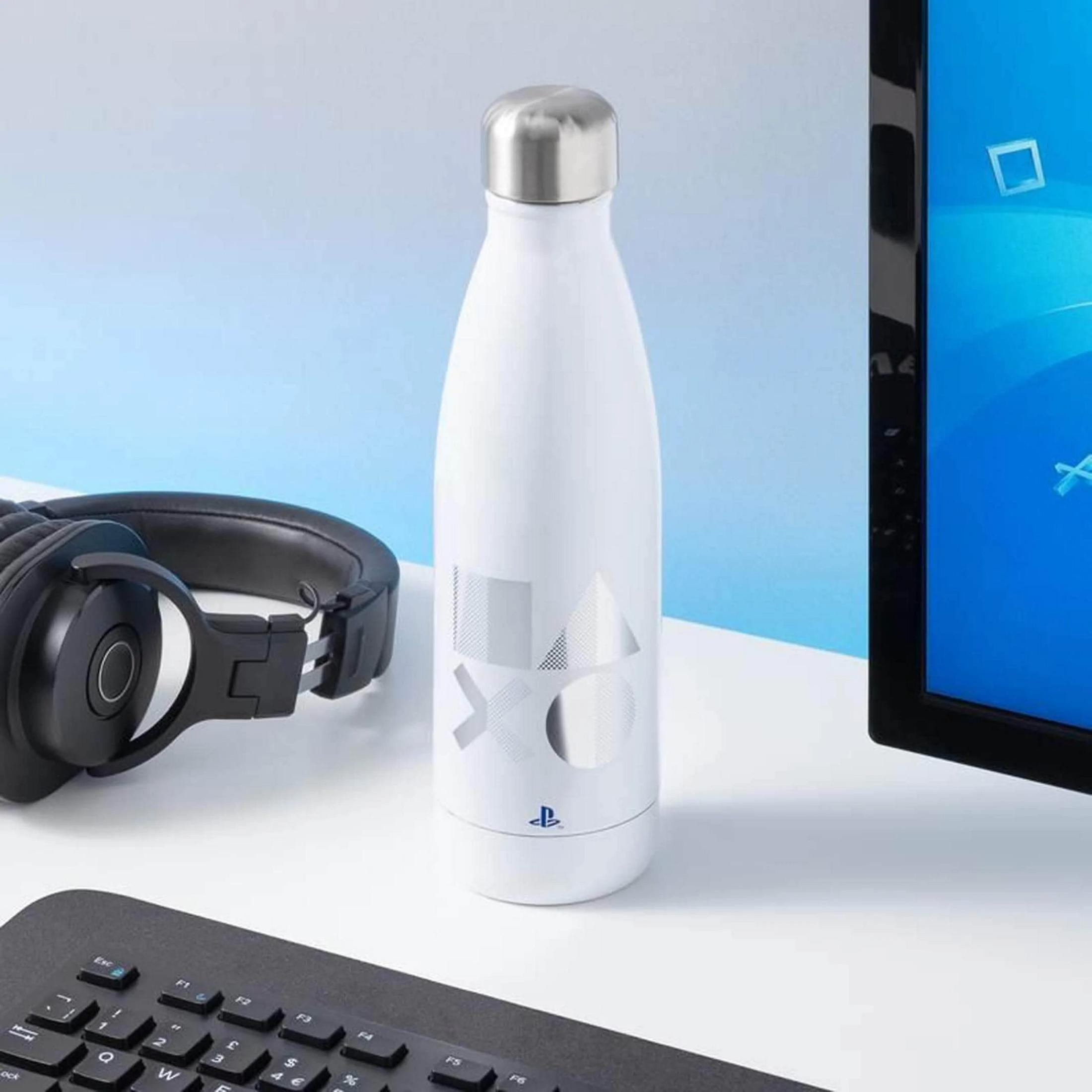 Weiße Wasserflasche mit PlayStation-Logo neben Kopfhörern und Tastatur.