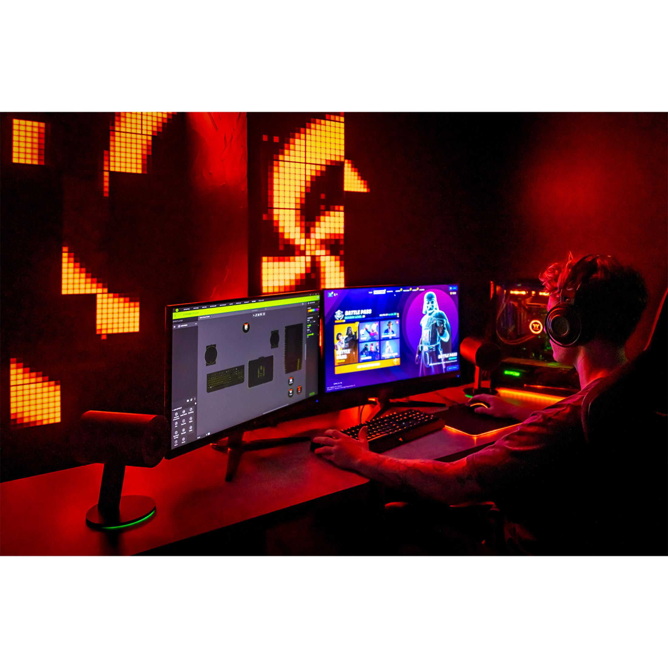 Gracz w słuchawkach gra na dwóch monitorach w czerwonym oświetleniu.
