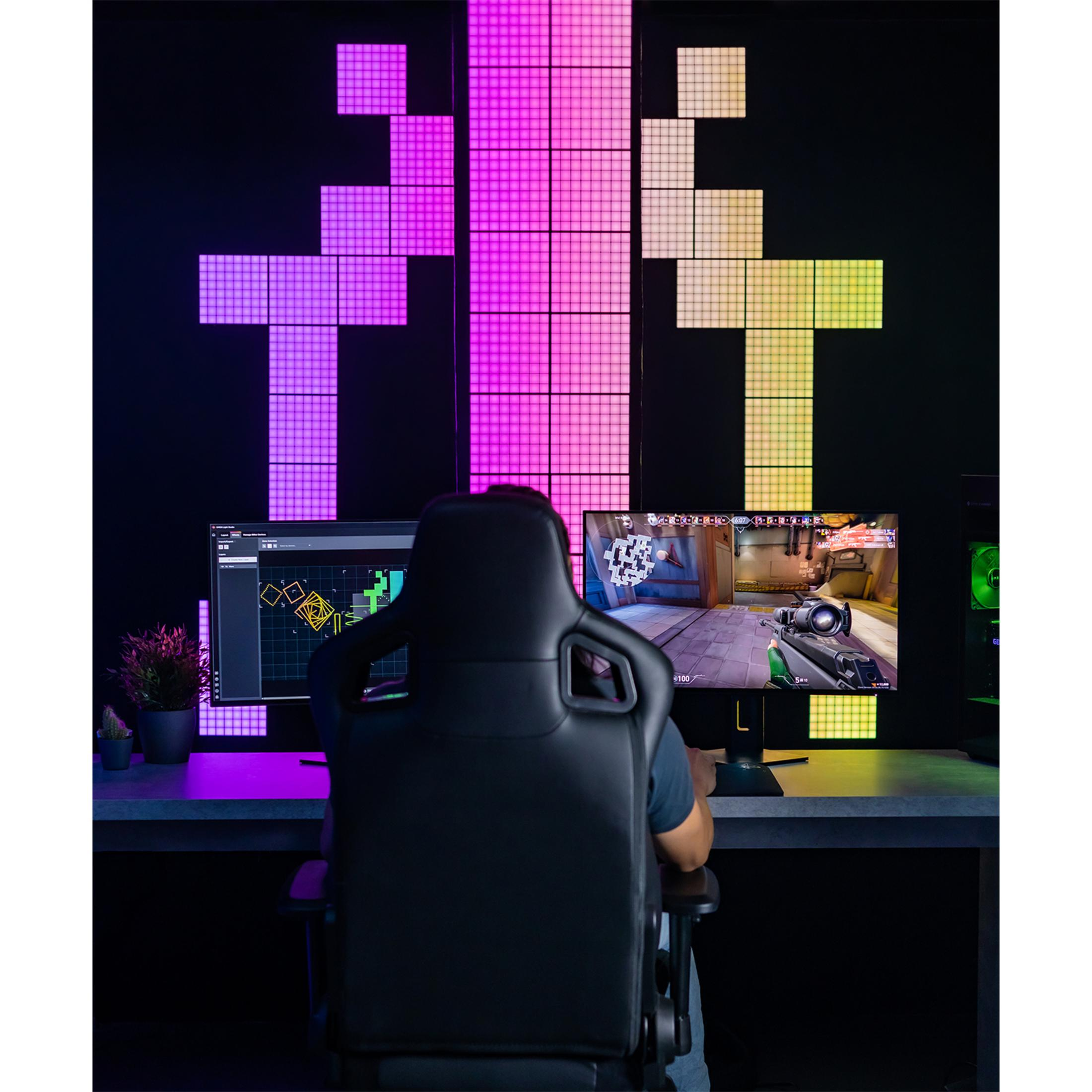 Gracz siedzi przed dwoma monitorami, oświetlony kolorowymi panelami.