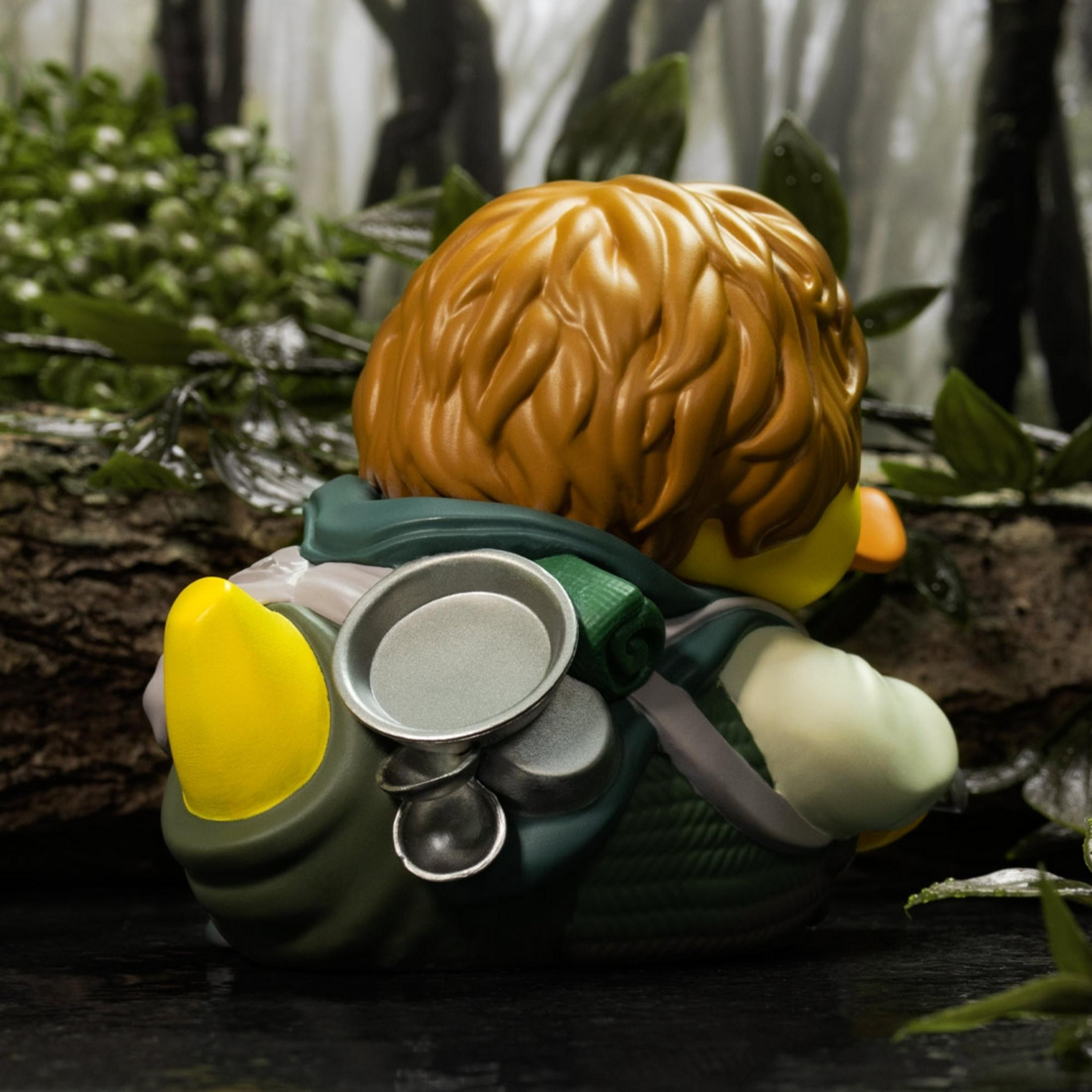 Ein Gummientchen mit braunem Haar und Rucksack im Wald.