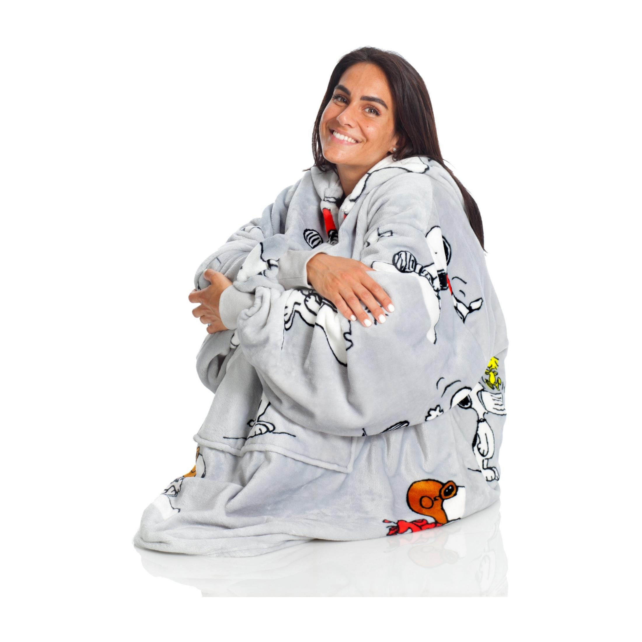 Una donna seduta in una felpa grigia con stampa Snoopy, sorridente.