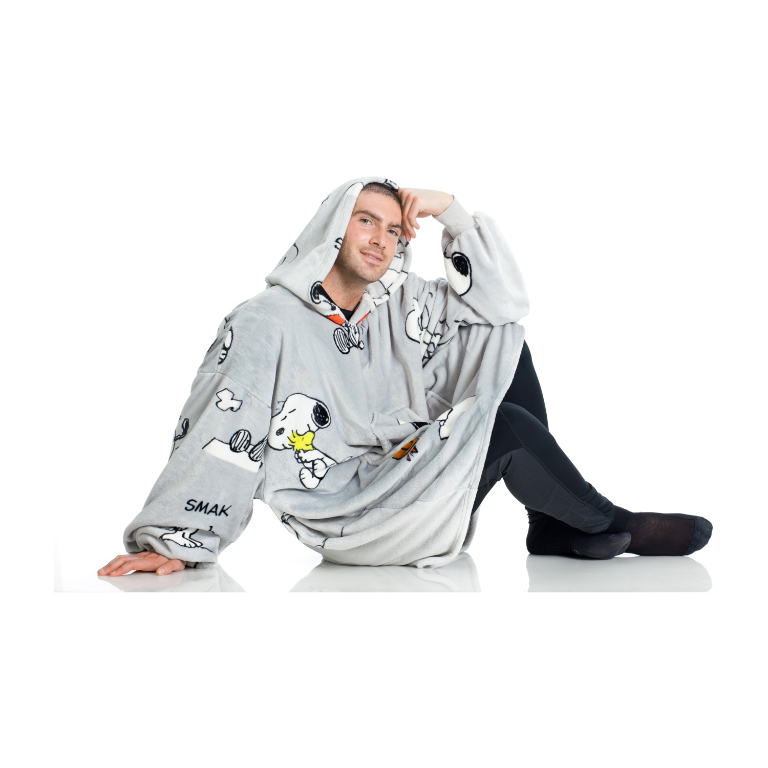 Un uomo seduto in una felpa grigia con personaggi di Snoopy, una mano sulla testa.