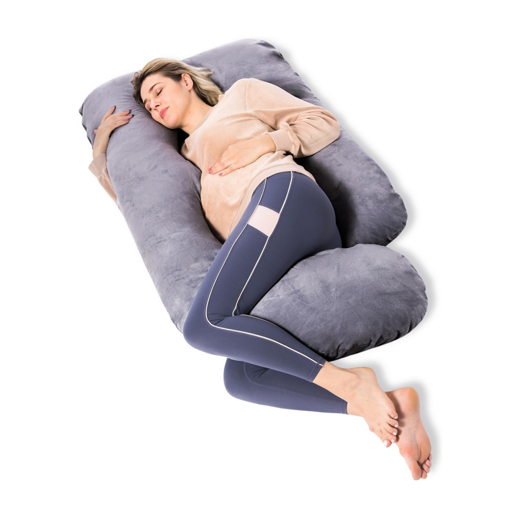 Schwangere Frau schläft auf einem grauen Kissen. Sie trägt ein beige Pullover und blaue Leggings.