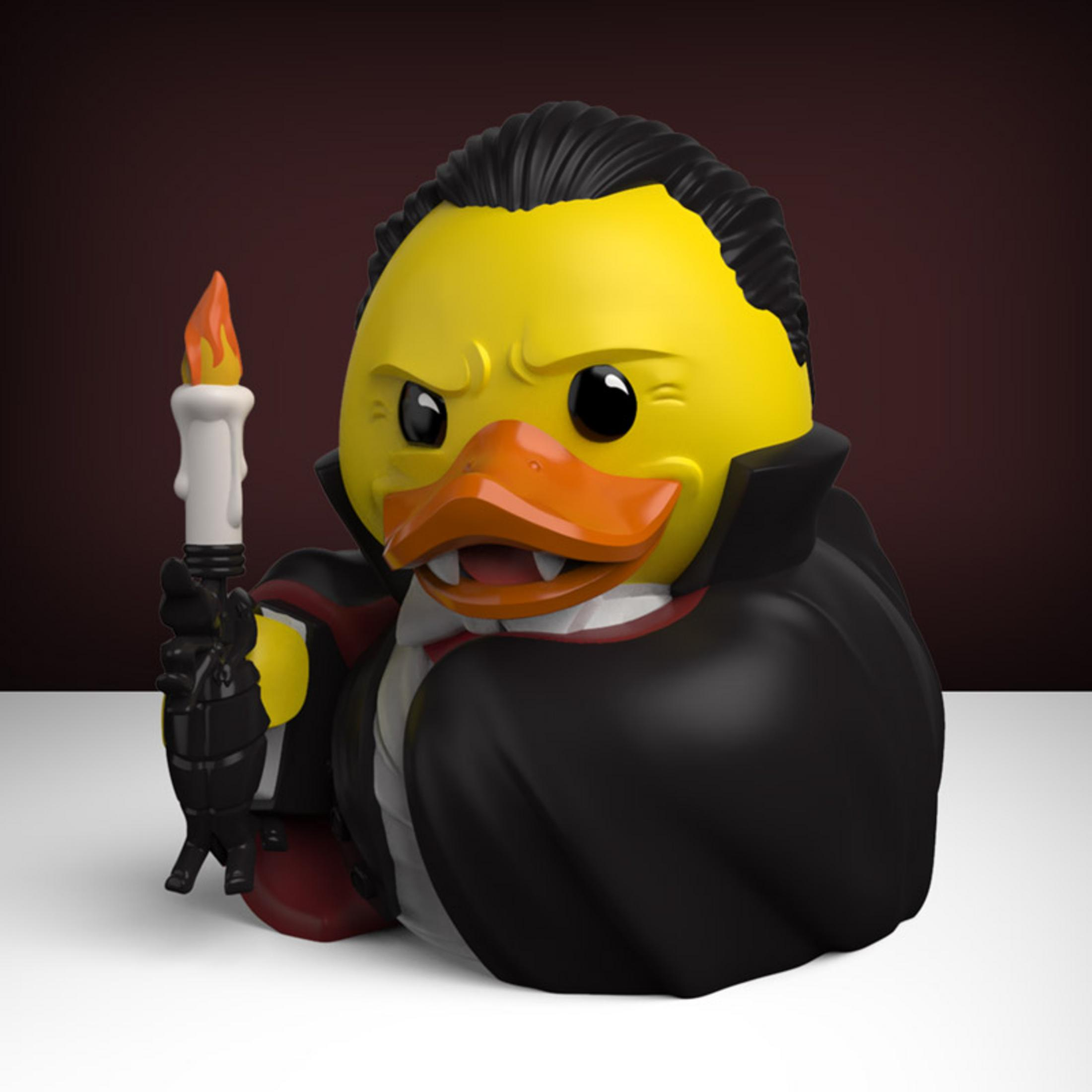 Gelbe Gummi-Ente als Vampir mit Kerze, schwarzem Umhang und roten Akzenten.