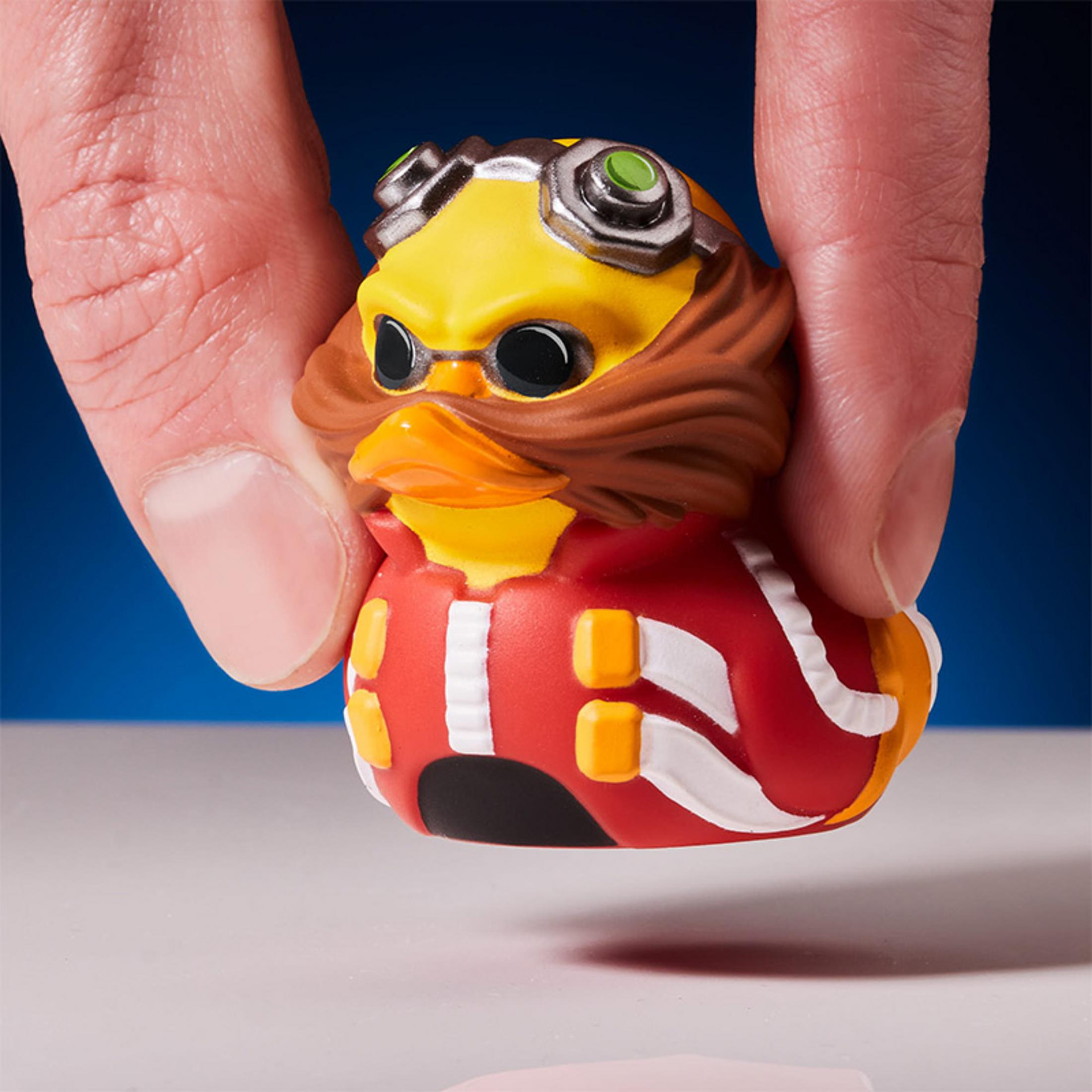 Eine Hand hält eine gelbe Gummiente im Stil von Dr. Eggman mit braunem Schnurrbart.
