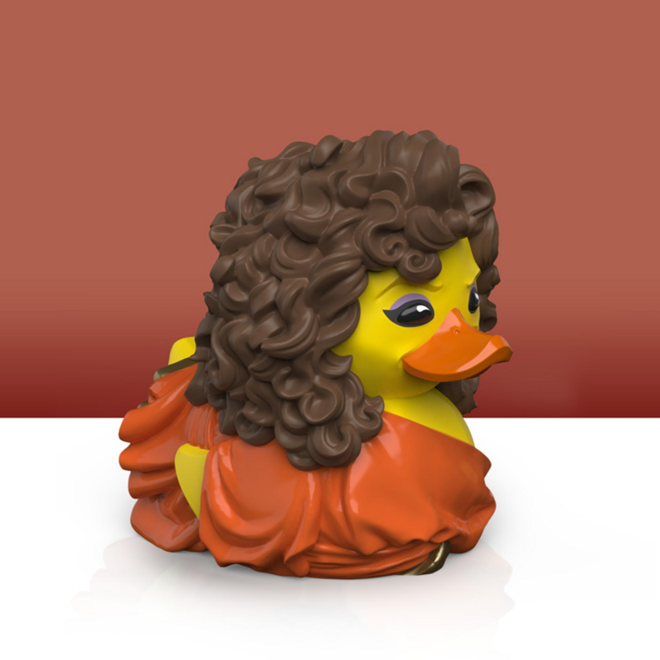 Gelbe Gummi-Ente mit braunen Locken und orangefarbenem Kleid.