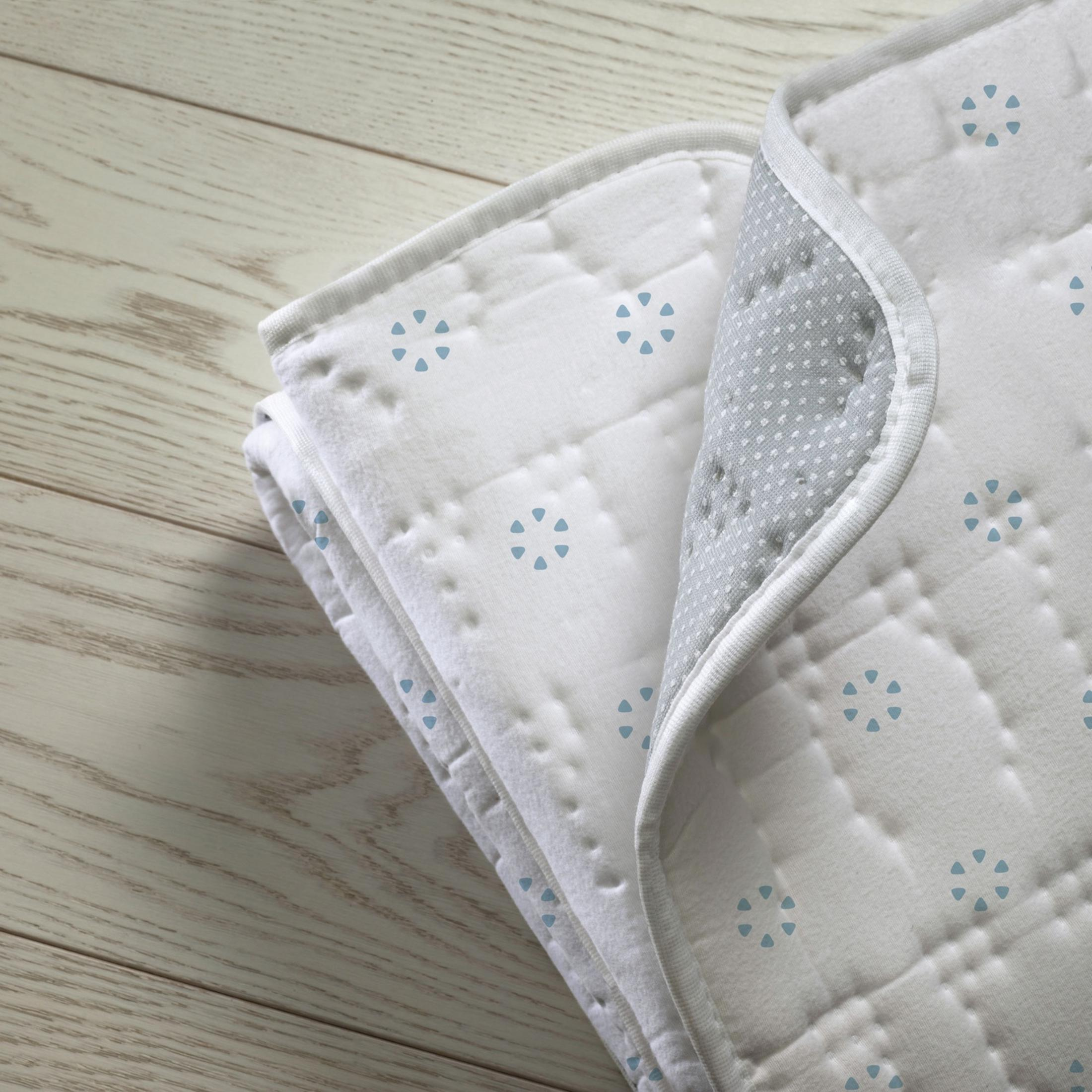 Tessuto bianco con motivi floreali blu, piegato su legno.