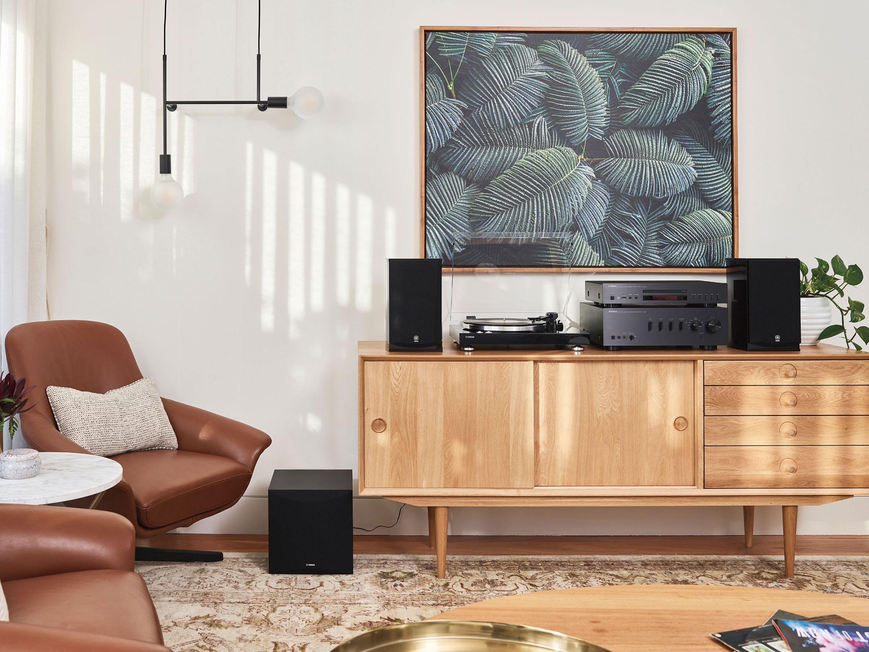 Poltrona in pelle marrone con cuscino, mobile in legno con apparecchiature audio.