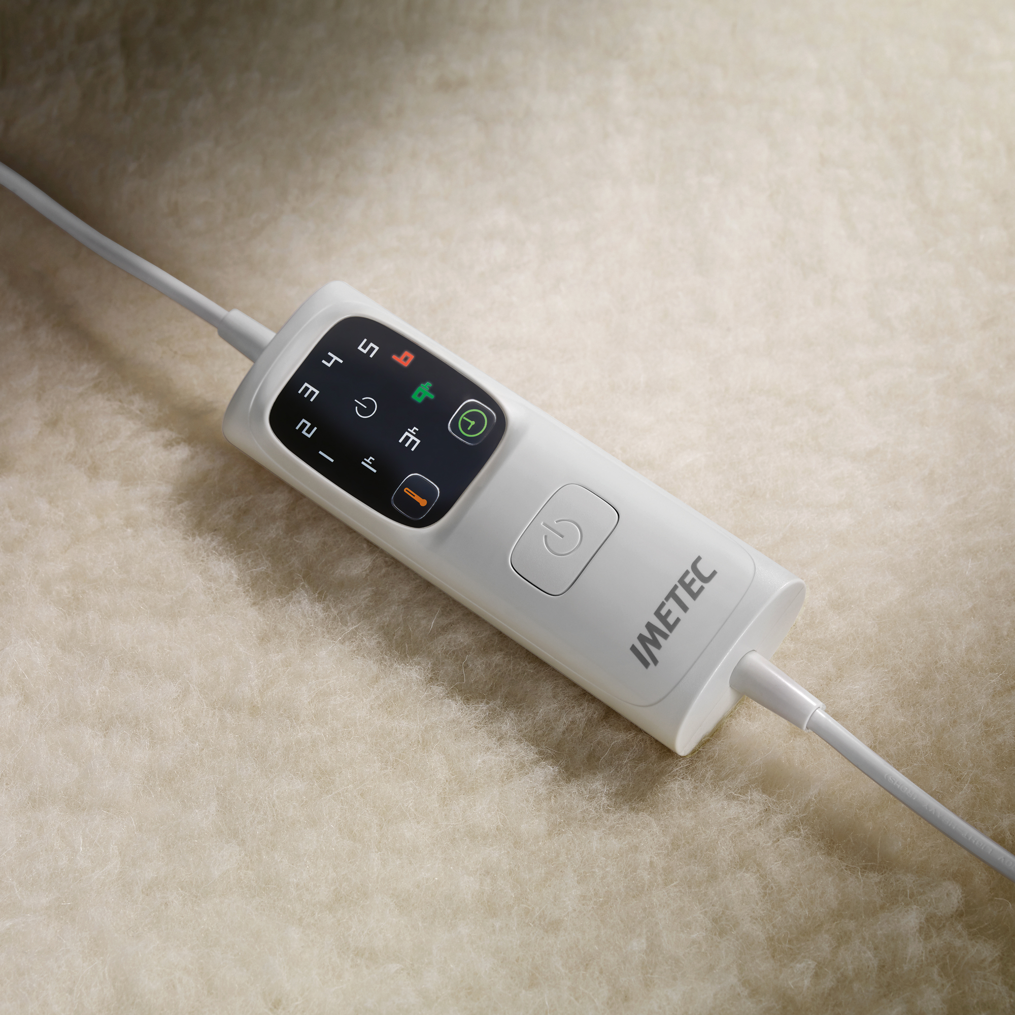 Un controlador blanco Imatec con pantalla digital sobre una superficie peluda color crema.