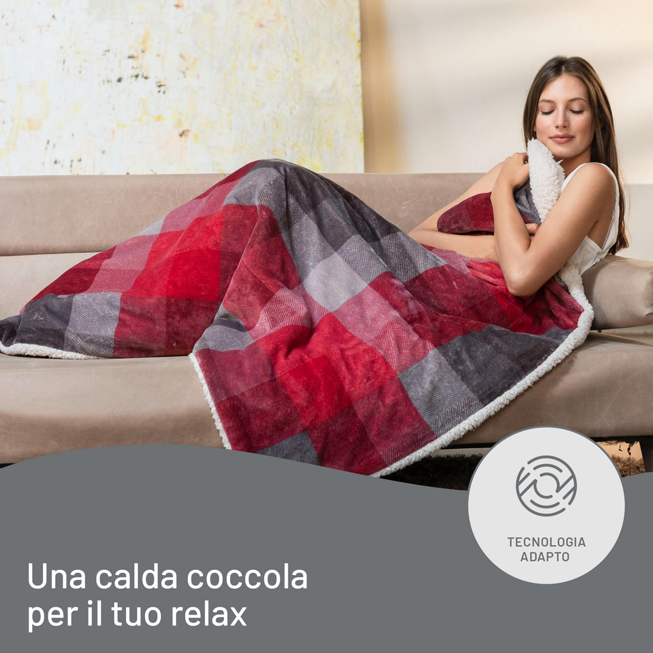 Una mujer se relaja en un sofá, envuelta en una manta a cuadros.