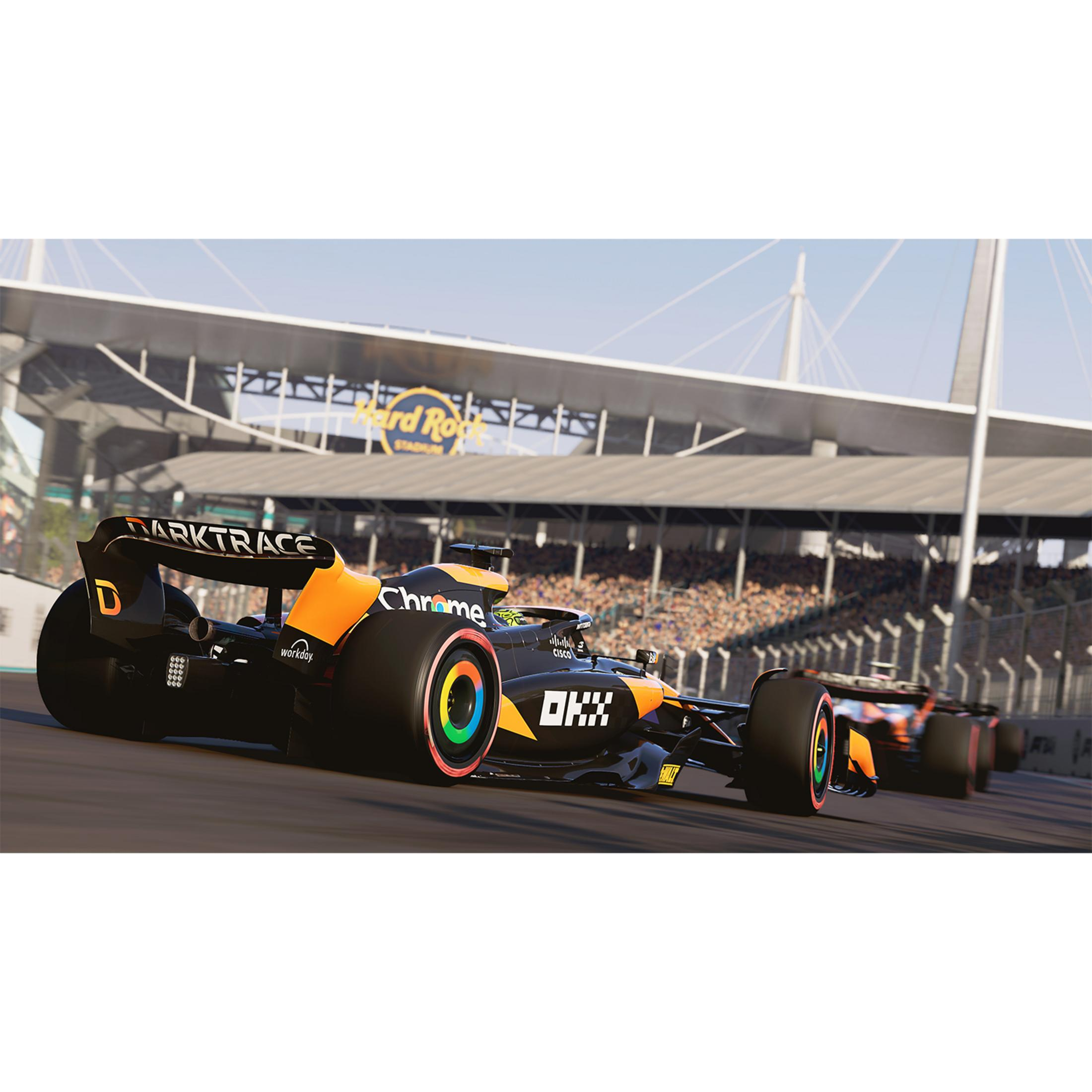 Un'auto di Formula 1 nera e arancione corre su una pista con uno stadio sullo sfondo.