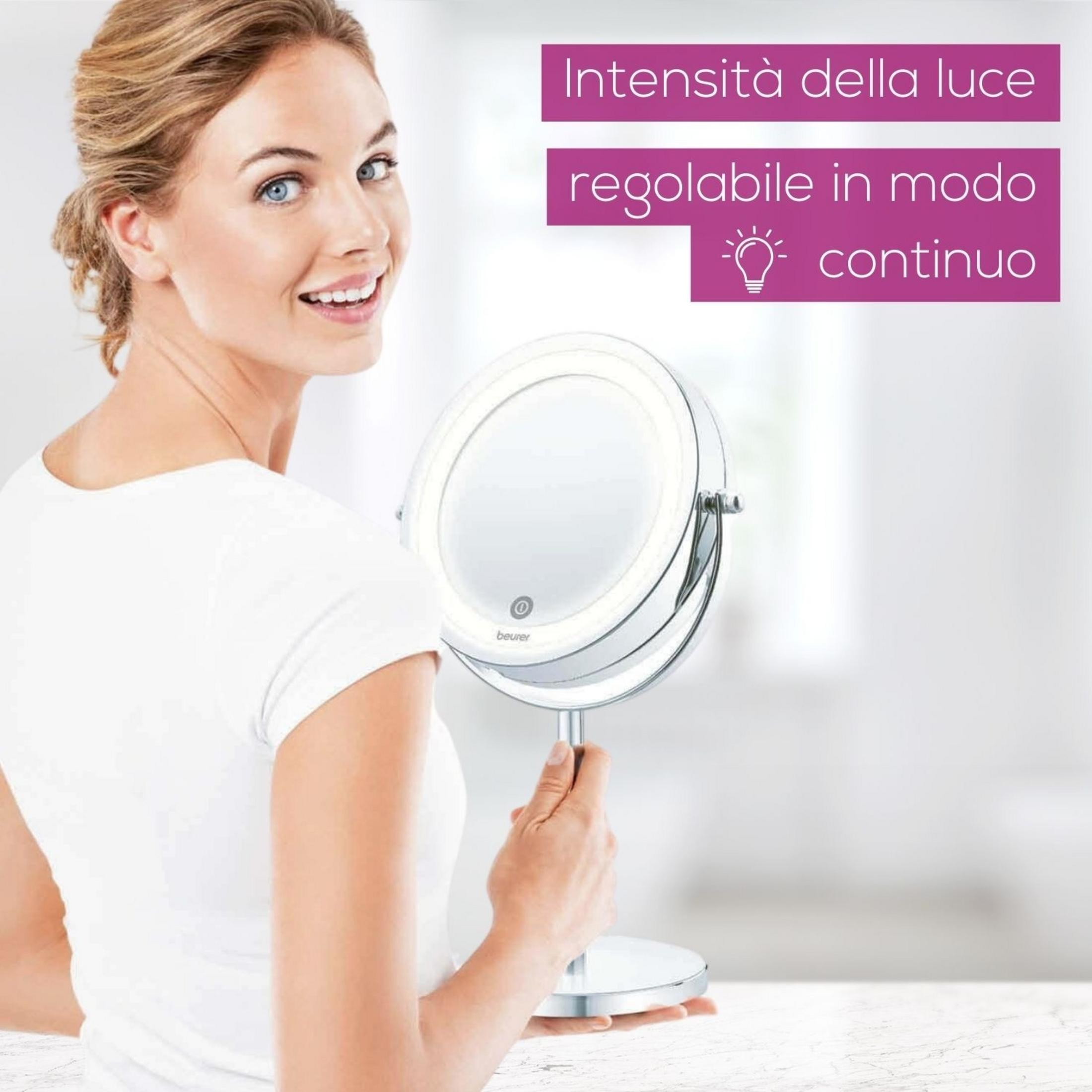 Una donna con occhi blu tiene uno specchio per il trucco illuminato.
