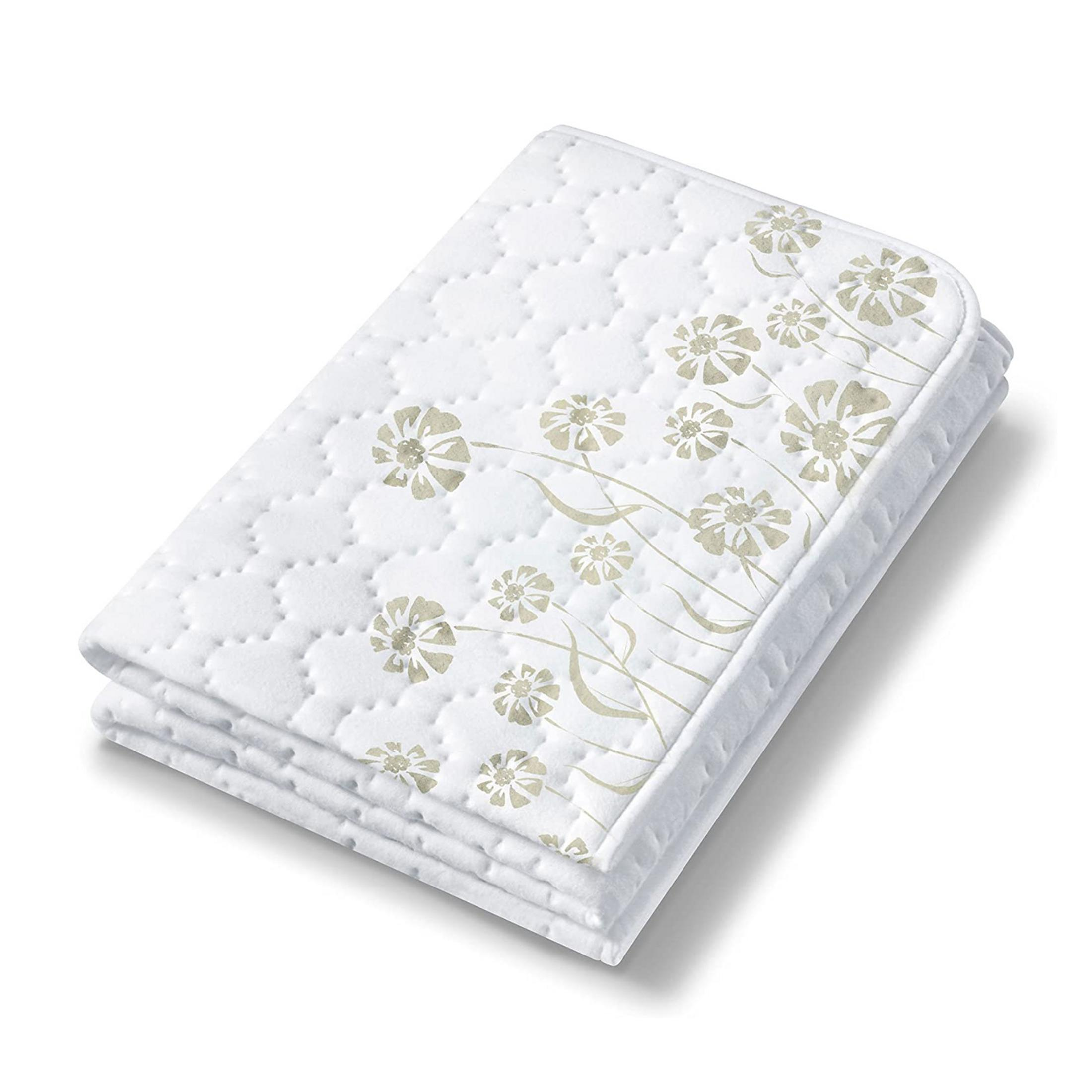 Eine weiße, gesteppte Decke mit dezenten Blumenmustern in Beige, auf weißem Hintergrund.