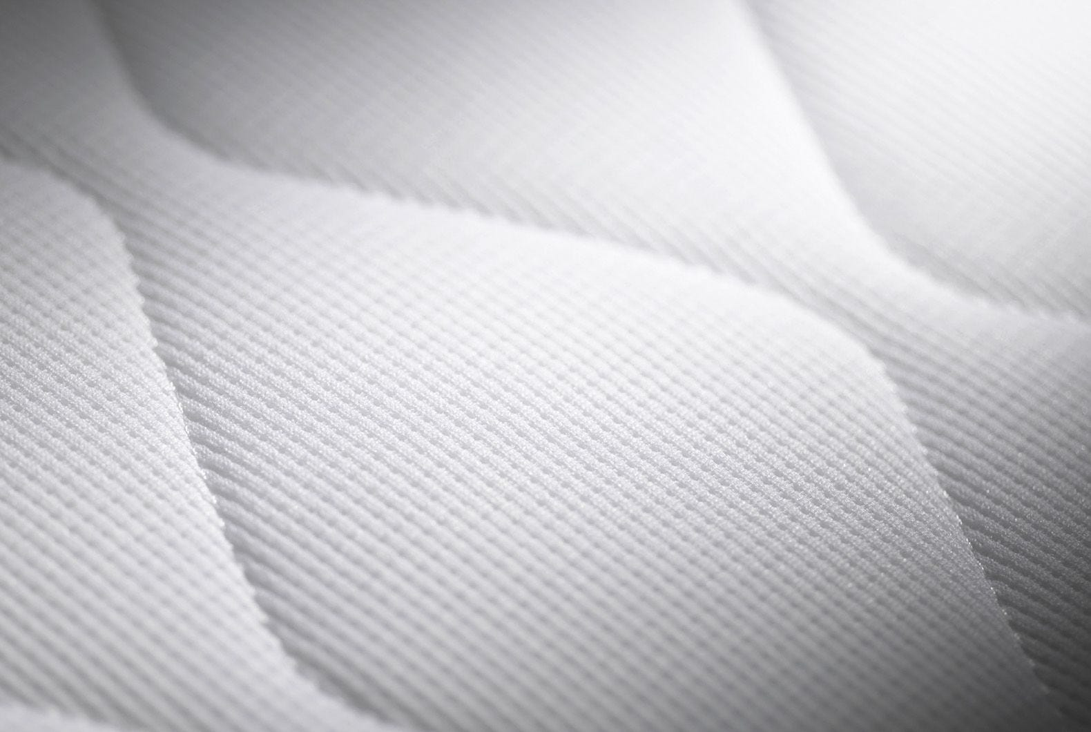 Primer plano de tela blanca con líneas acolchadas y sombras.