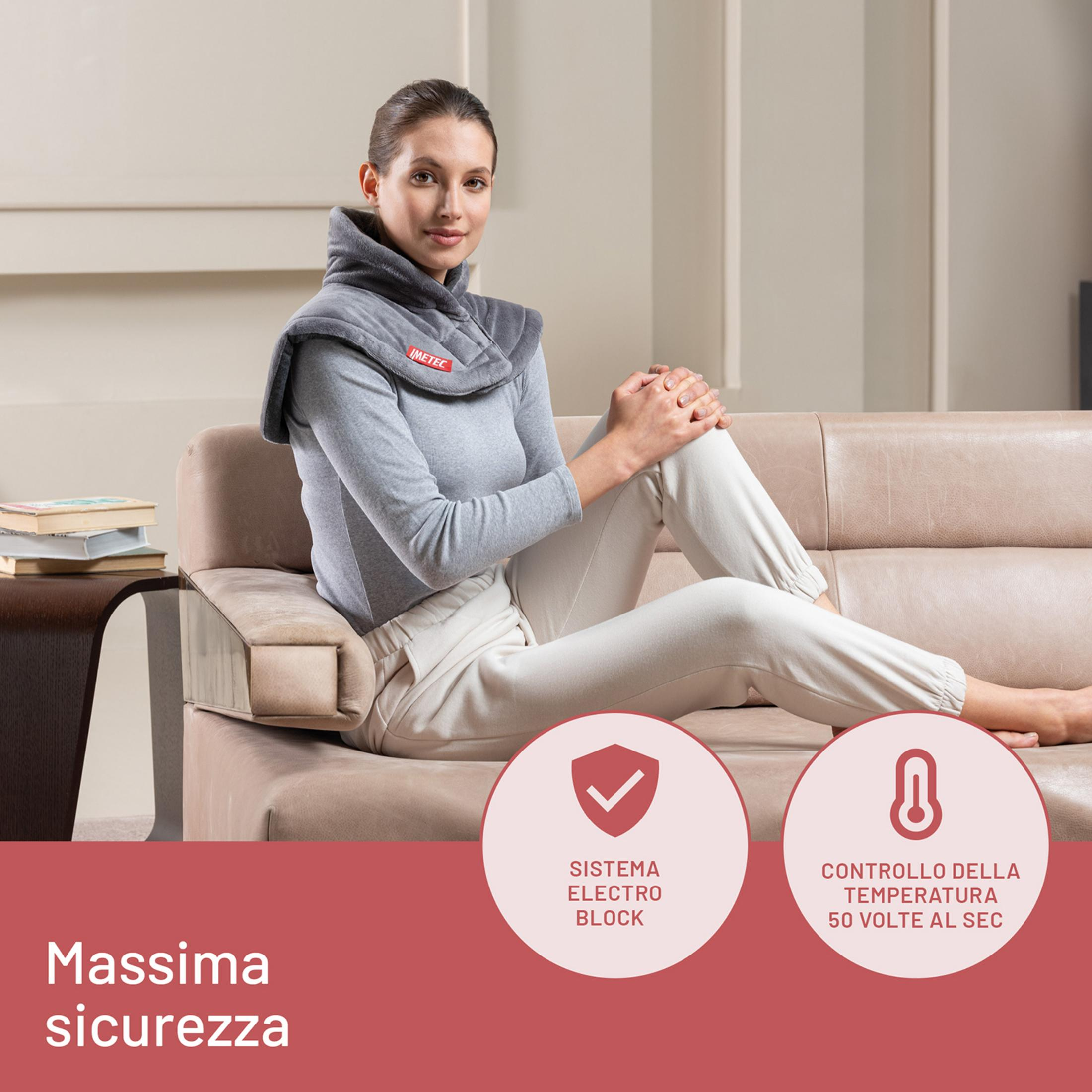 Mujer sentada en un sofá con una almohadilla térmica gris.