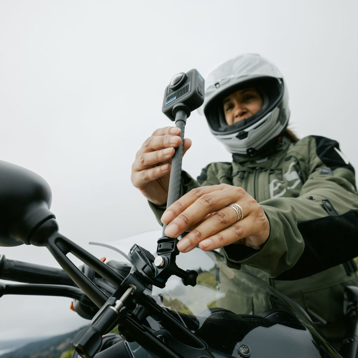 Motorradfahrerin mit Helm stellt Actionkamera am Lenker ein.