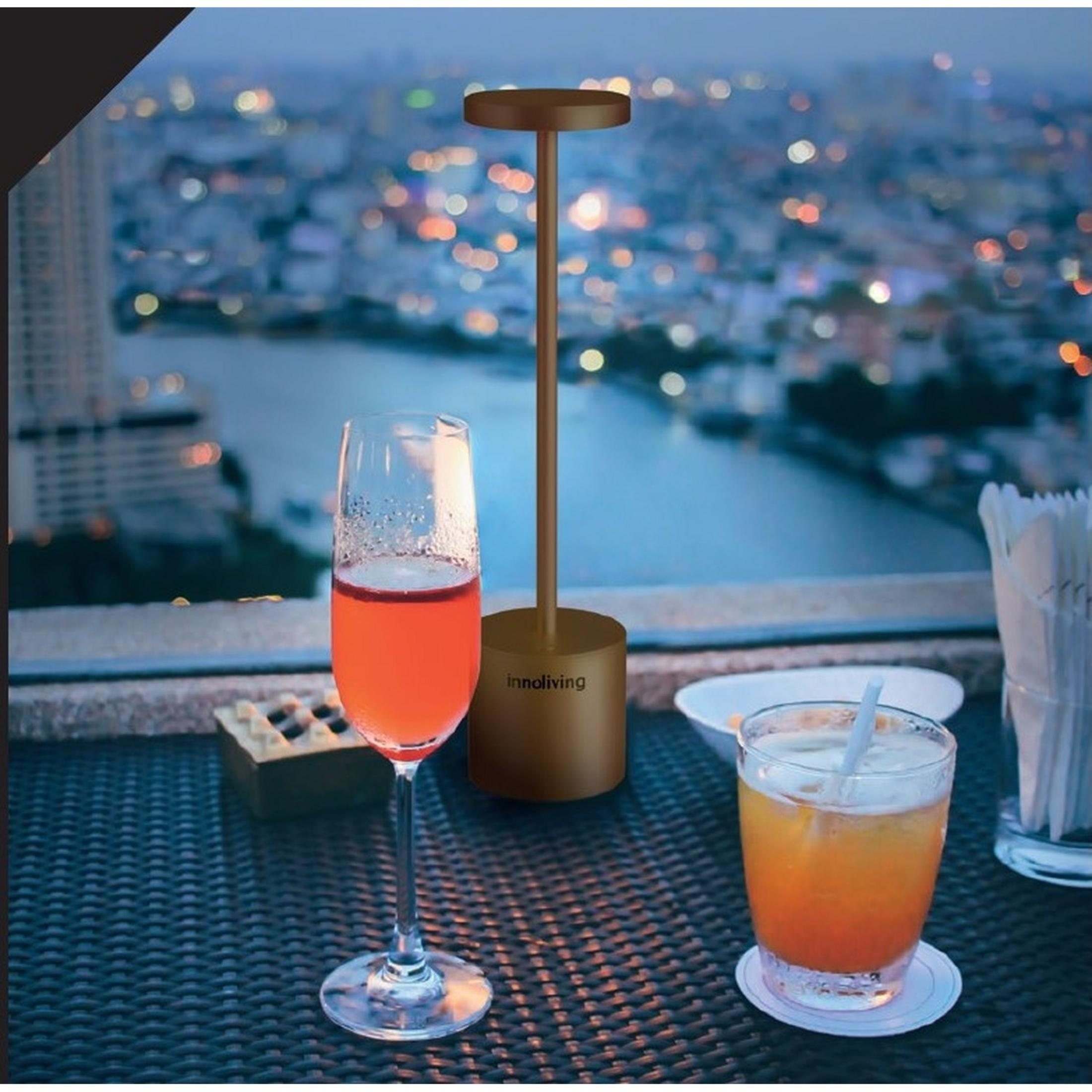 Due drink e una lampada su un tavolo con vista sulla città di notte.