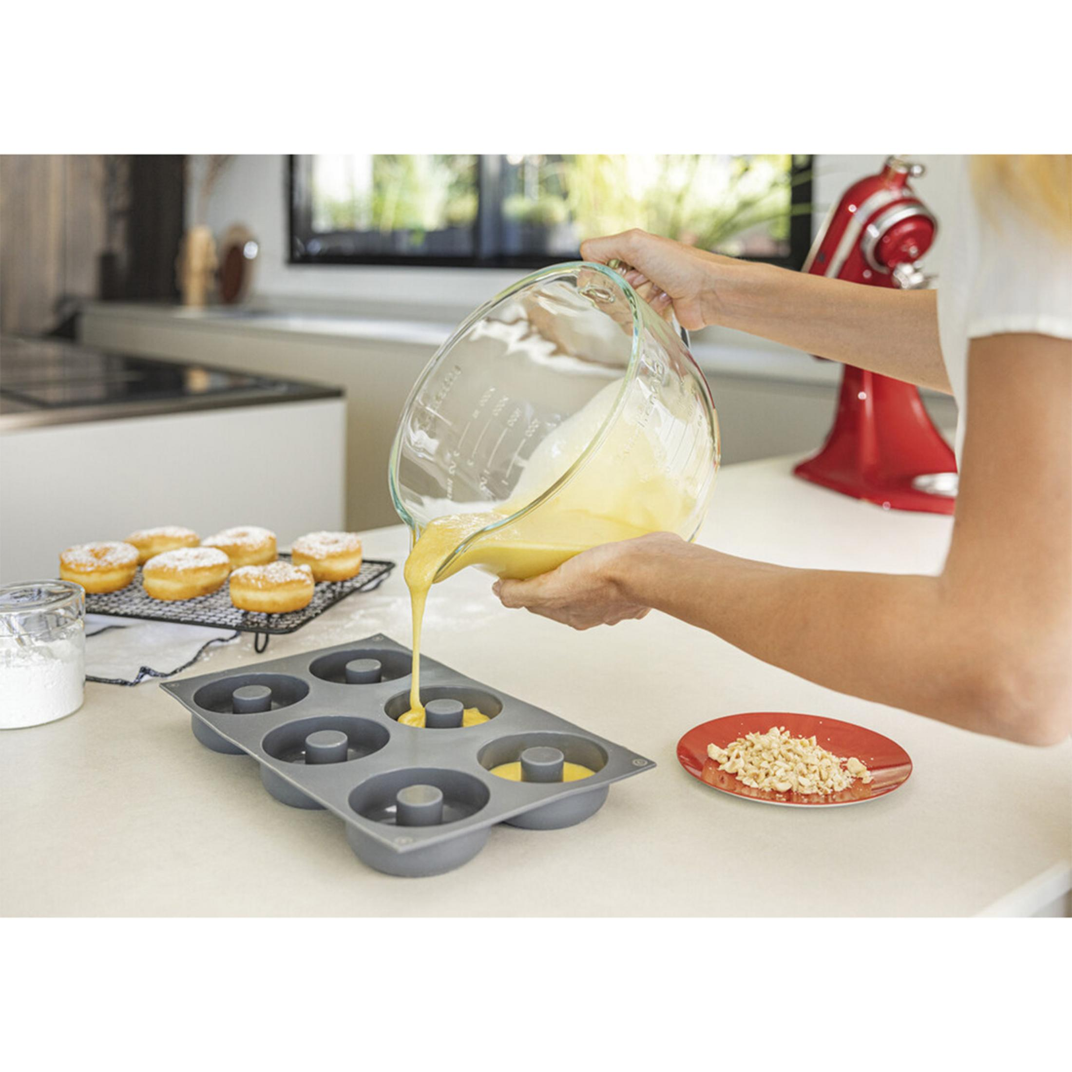 Flüssiger Teig wird aus einer Schüssel in eine Donut-Backform gegossen.