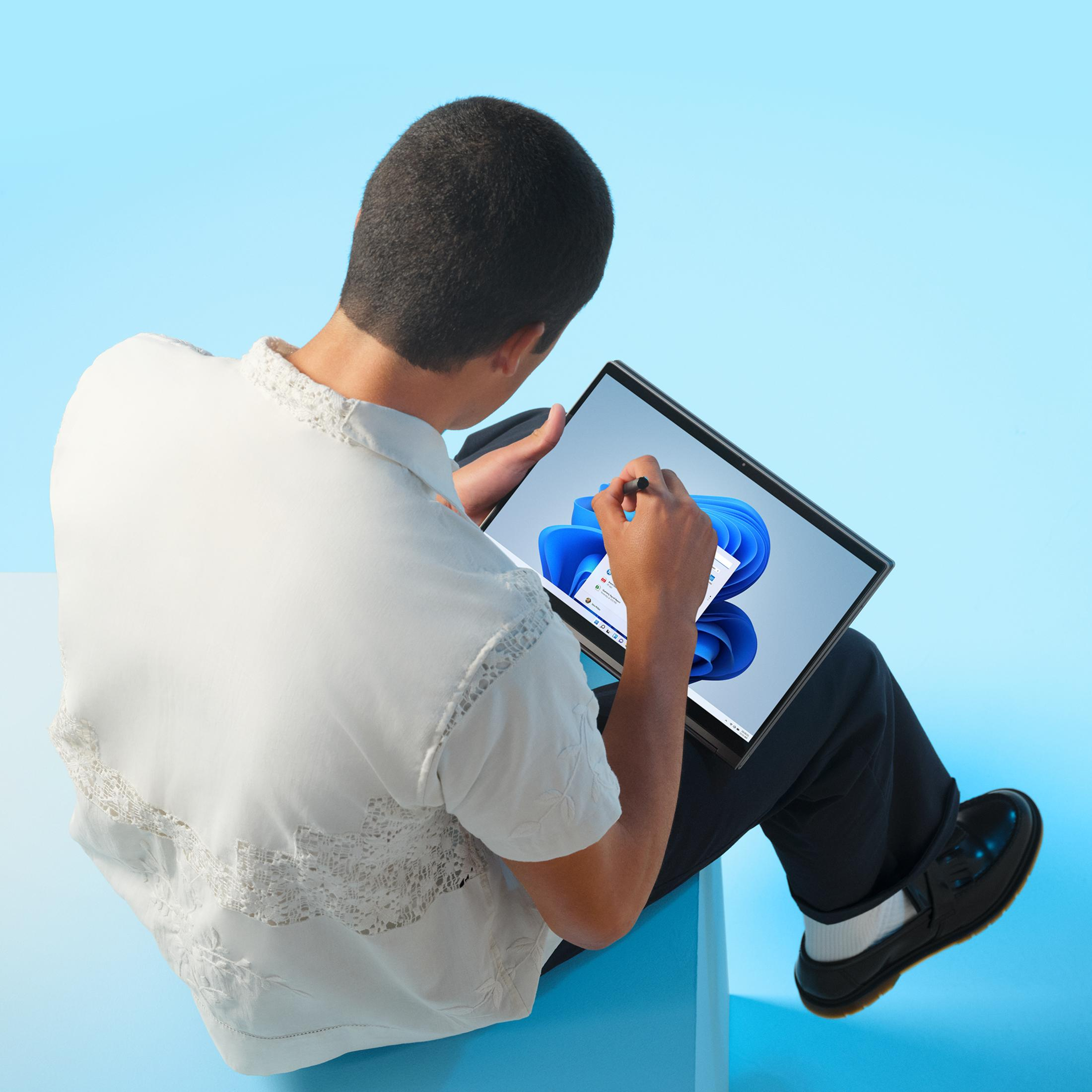 Mężczyzna w białej koszuli używa rysika na tablecie na niebieskim tle.