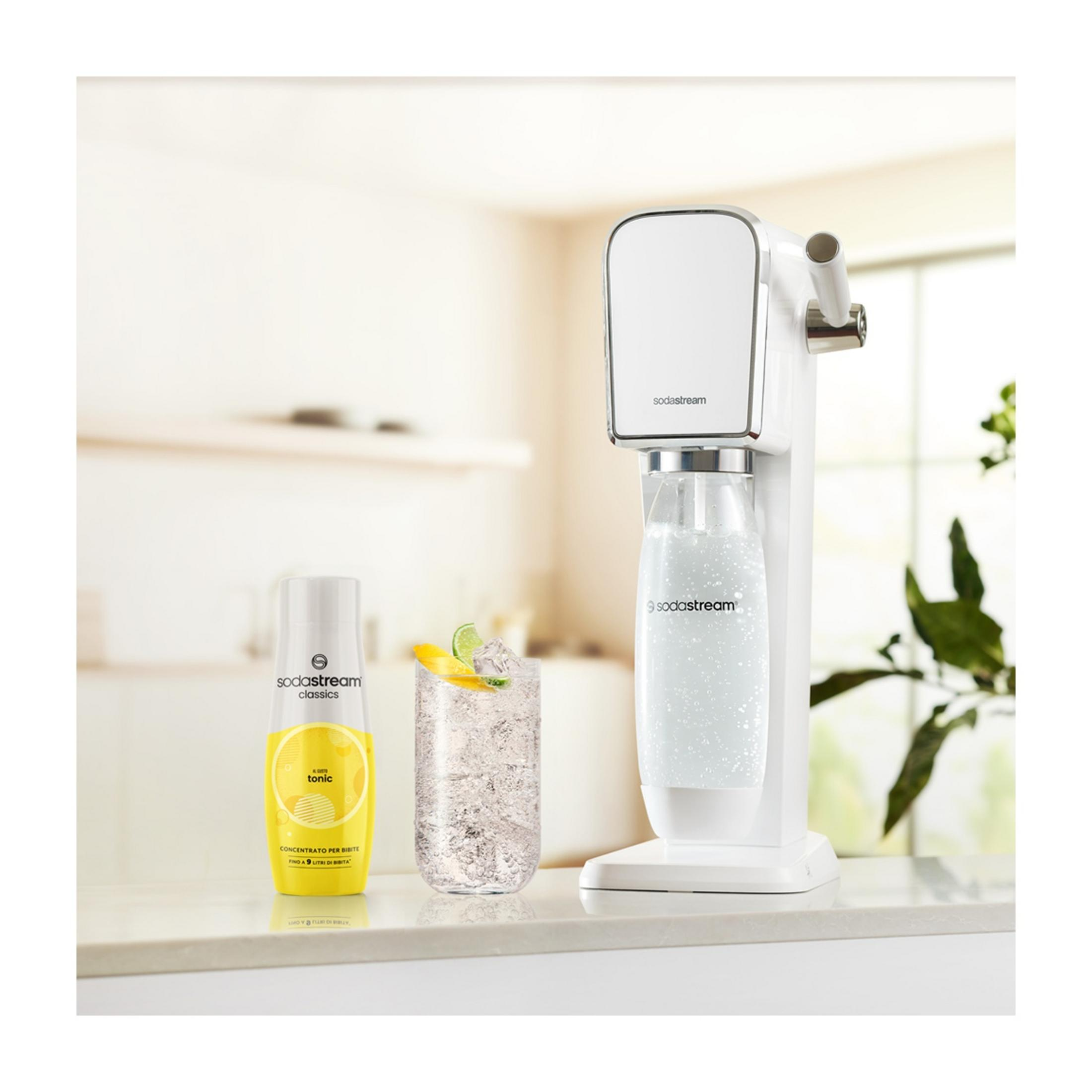 Una macchina SodaStream con una bottiglia di tonica e un bicchiere di bevanda.