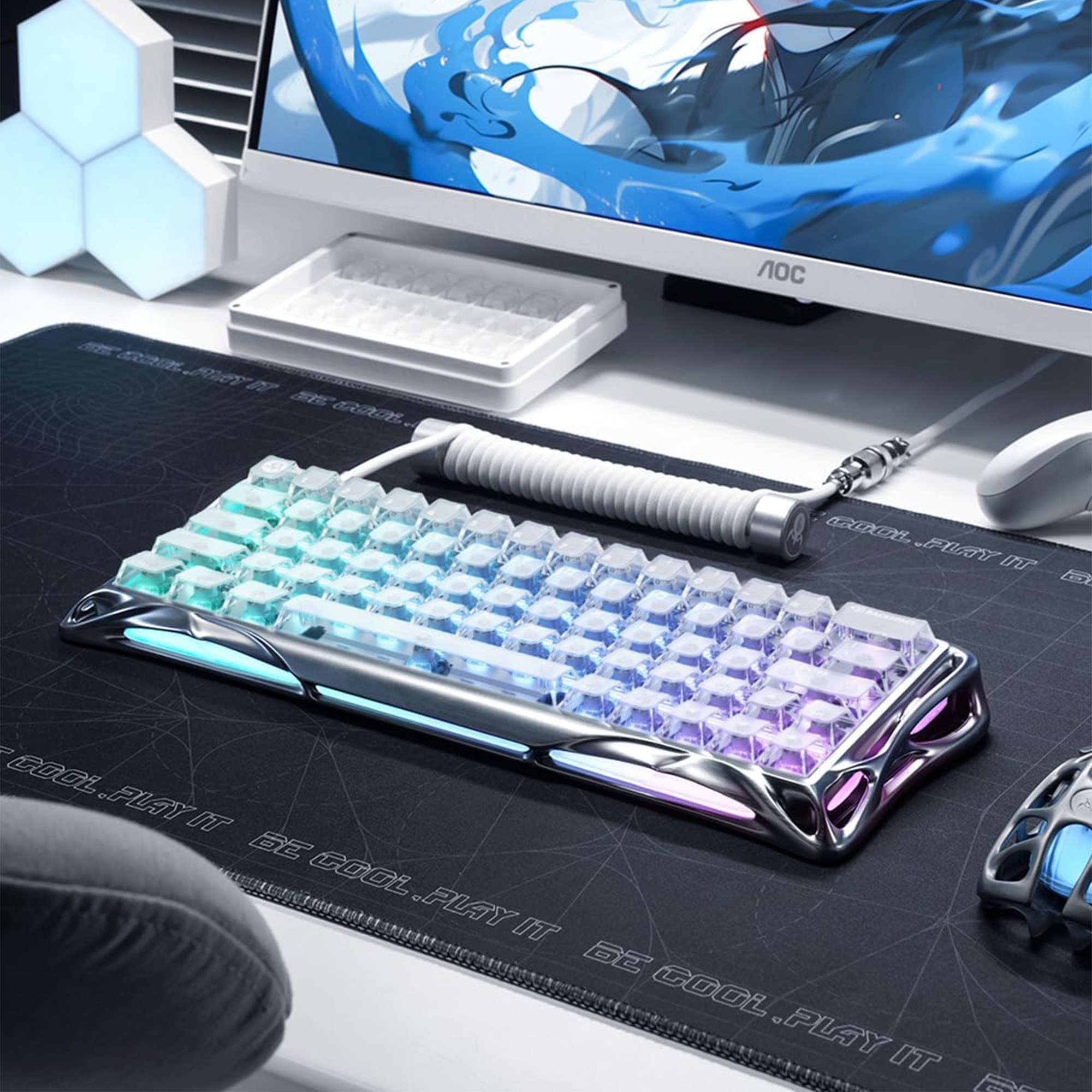 RGB aydınlatmalı bir oyuncu klavyesi, monitörün yanında siyah bir matın üzerinde duruyor.