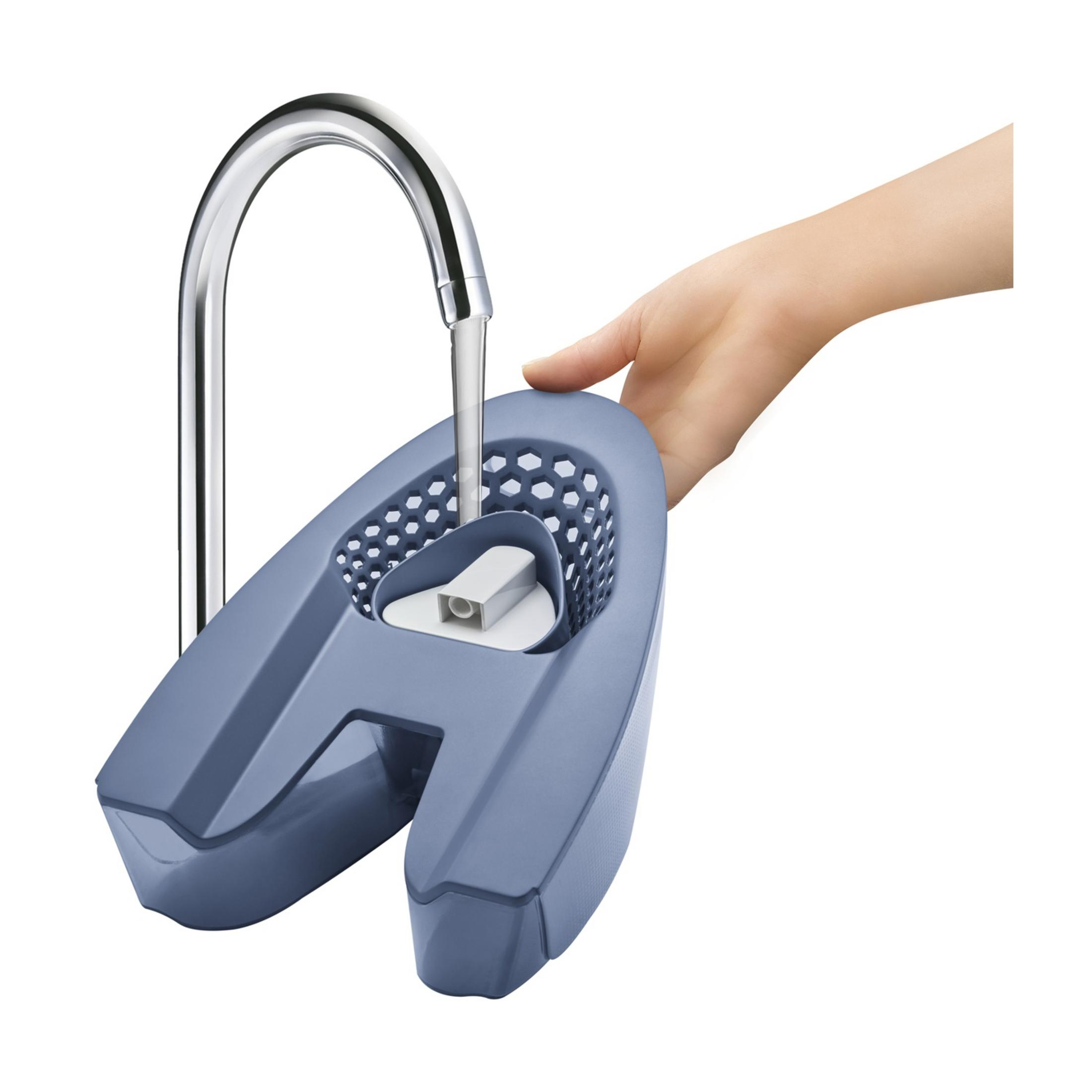 Une main tient un nettoyeur bleu sous l'eau courante d'un robinet.