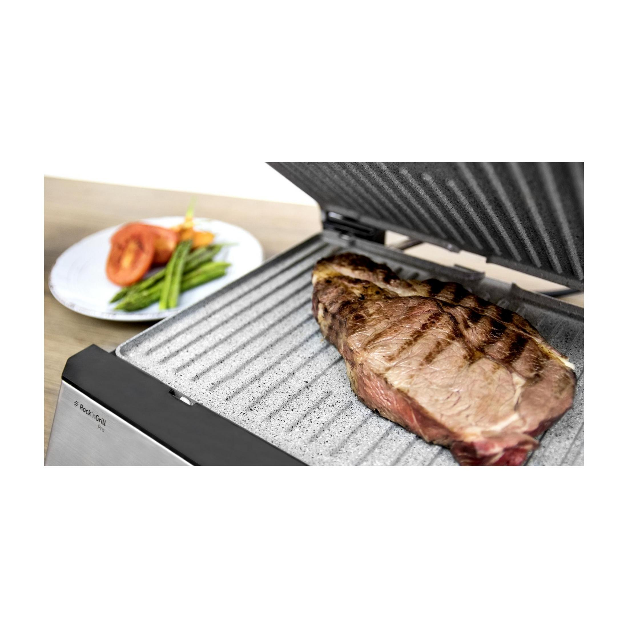 Grillowany stek na grillu, obok talerza warzyw.