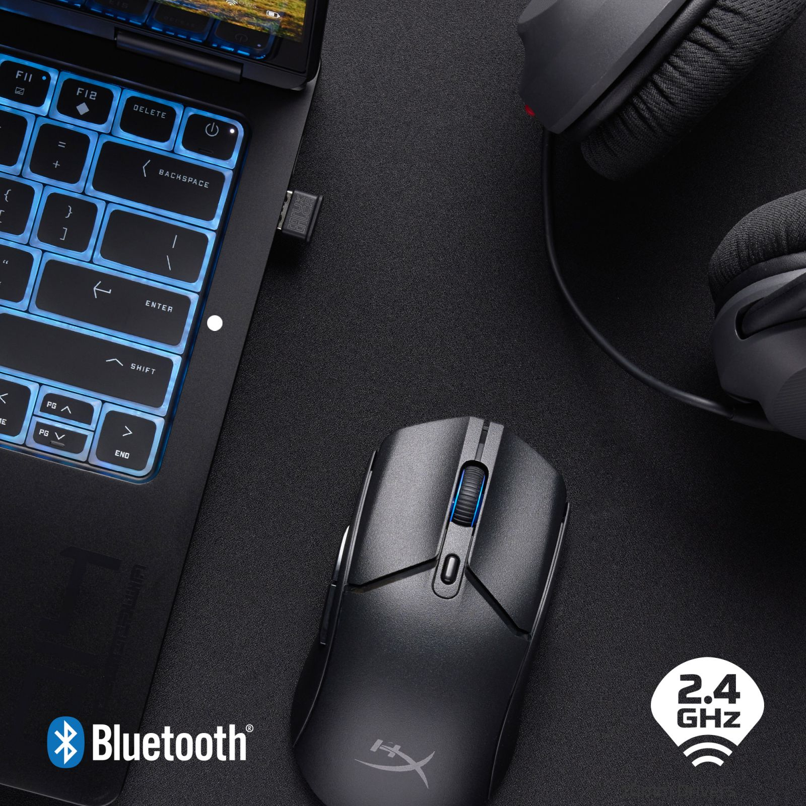 Czarny laptop z niebiesko podświetlanymi klawiszami, myszką i słuchawkami.