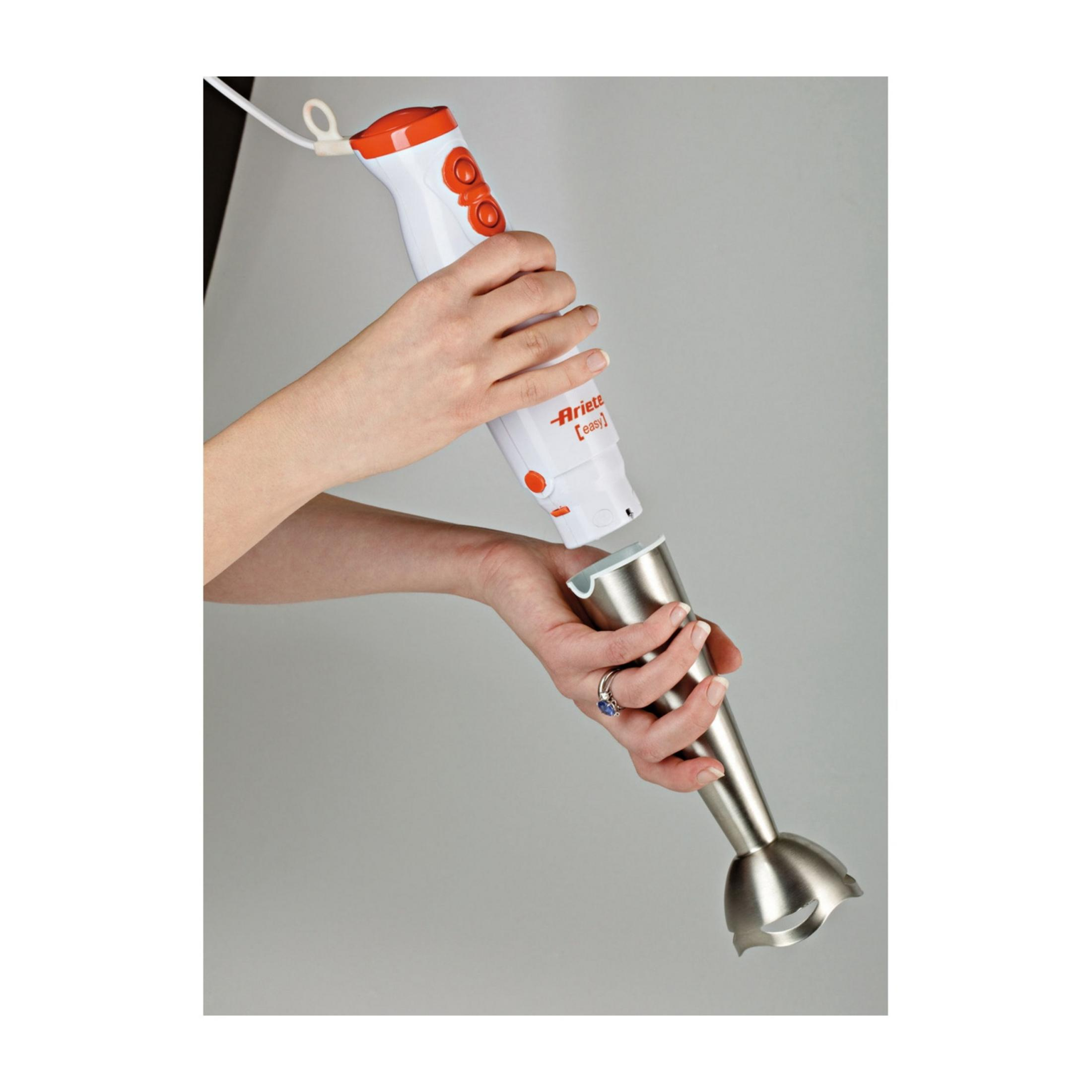 Ręka trzyma biały blender ręczny z pomarańczowymi przyciskami, rozkładając go.