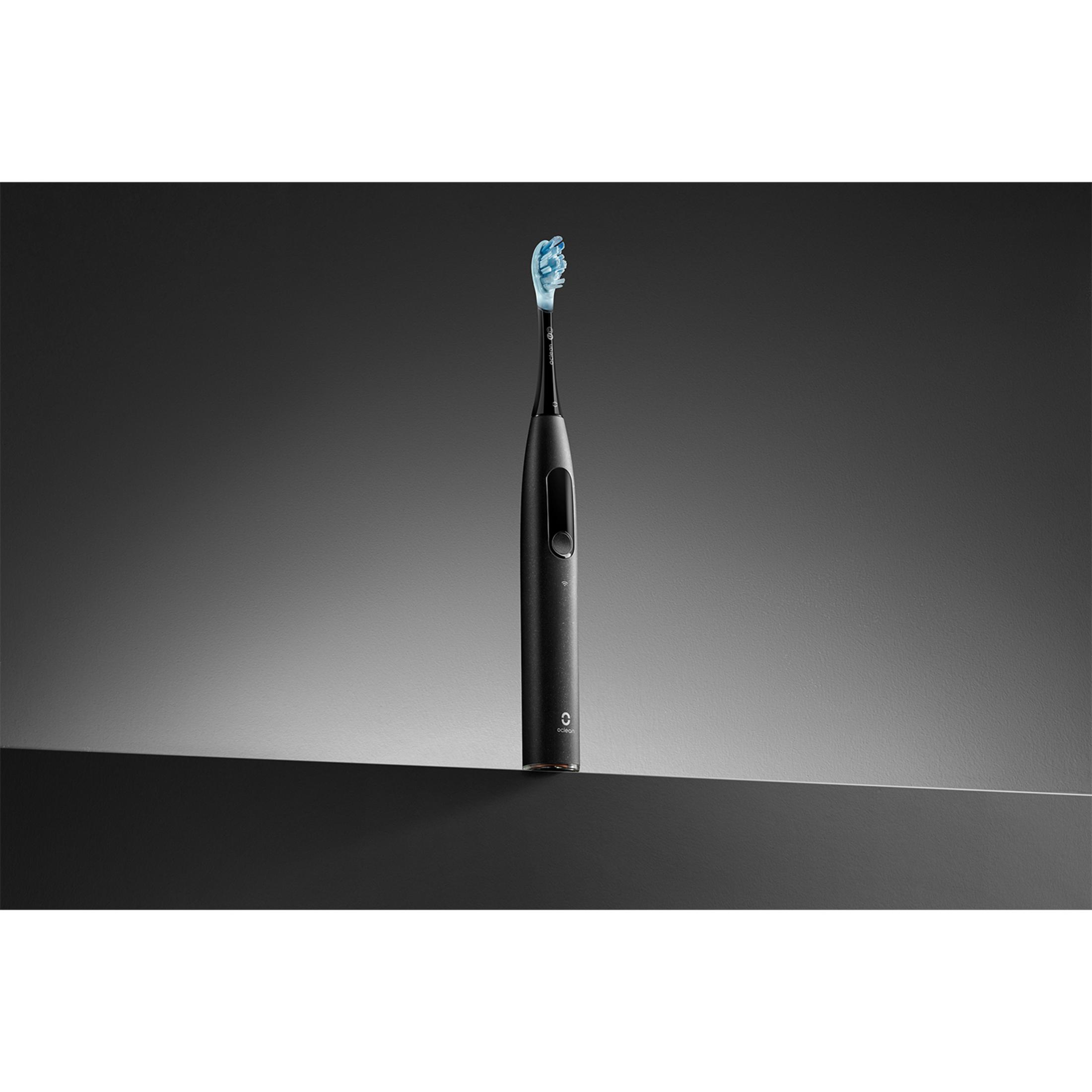 Eine schwarze elektrische Zahnbürste mit blauen Borsten steht auf einer dunklen Oberfläche.