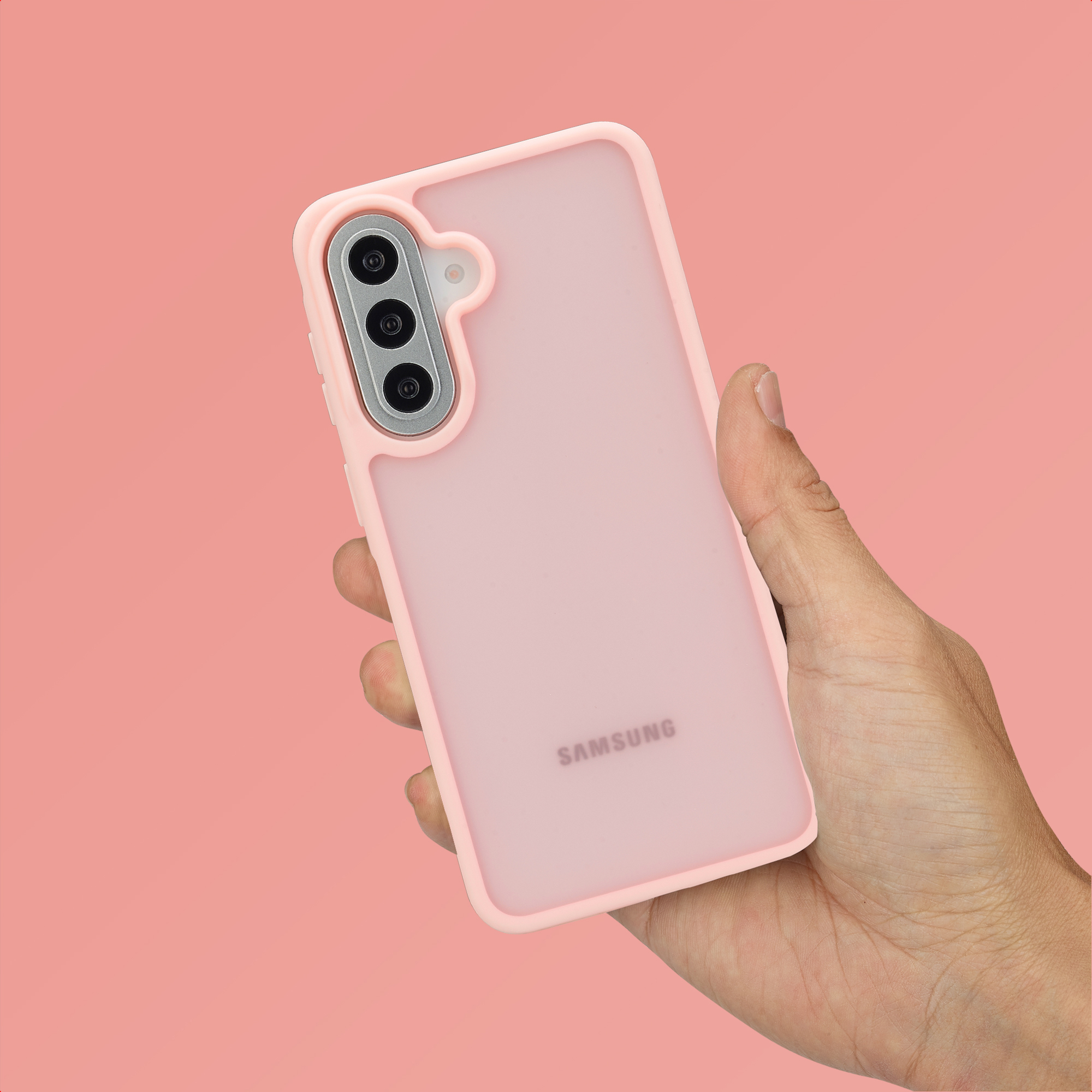 Une main tient un téléphone Samsung rose avec trois caméras au dos.