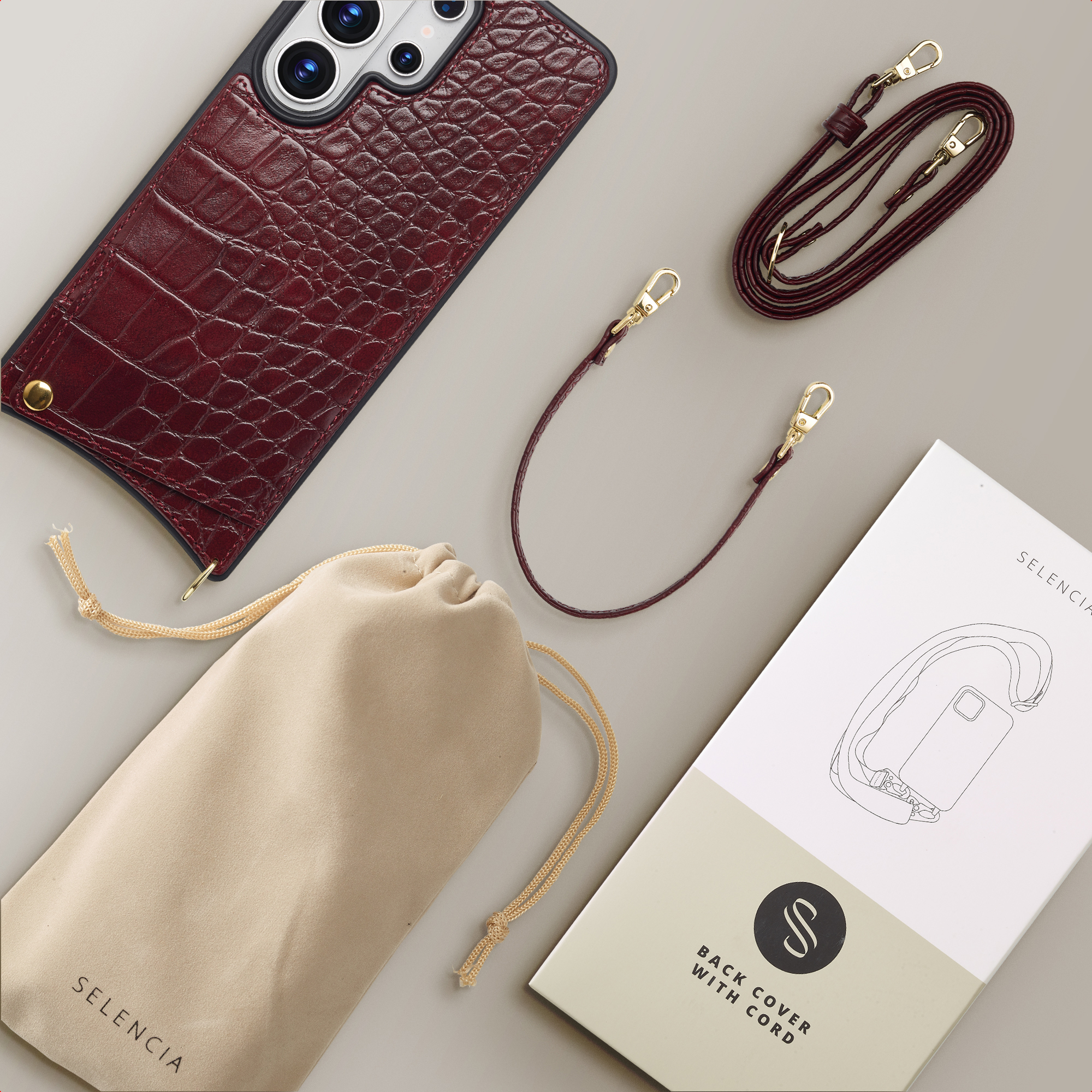 Coque de téléphone en cuir de crocodile rouge foncé avec cordon, pochette et emballage.
