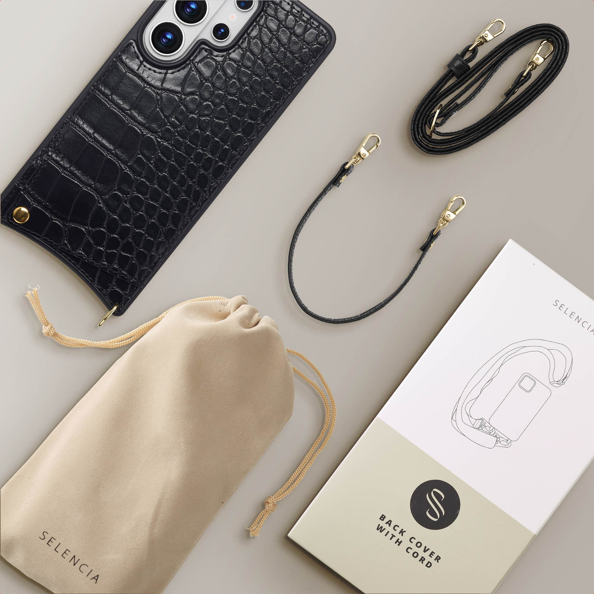 Zwarte krokodillenleren telefoonhoes met koord, buidel en verpakking.